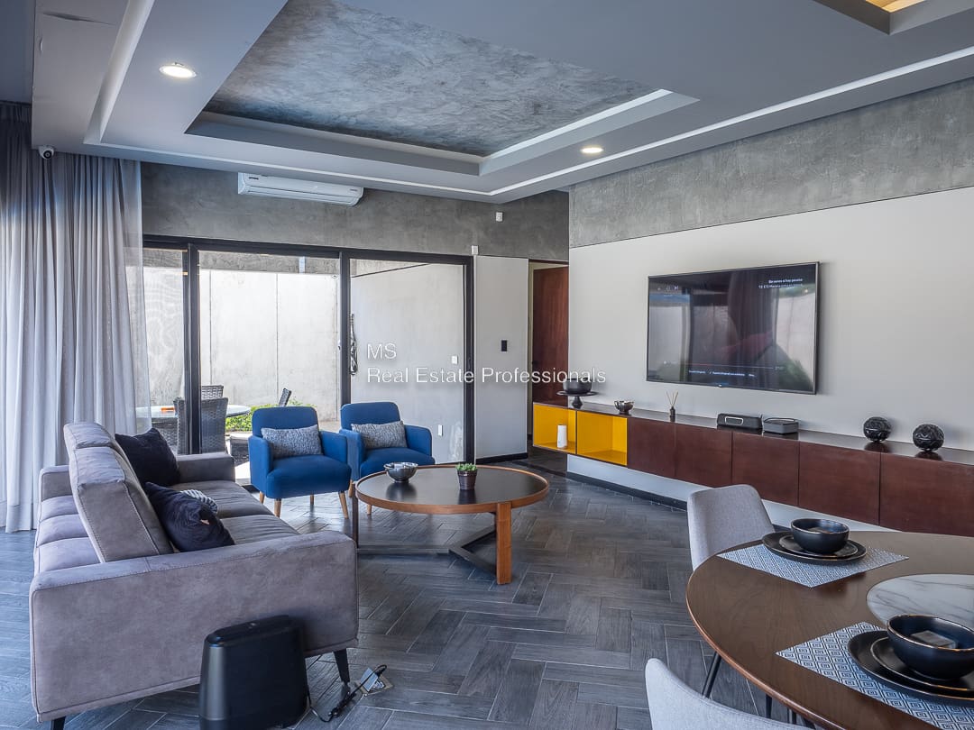 A living room with a couch, chairs and television.