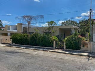 A house with bushes and trees in front of it.