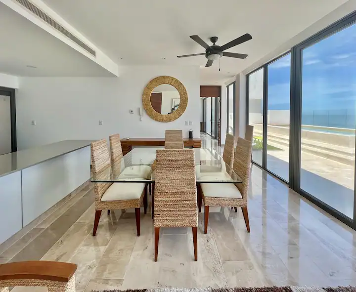 Modern dining room with beach view through glass walls.