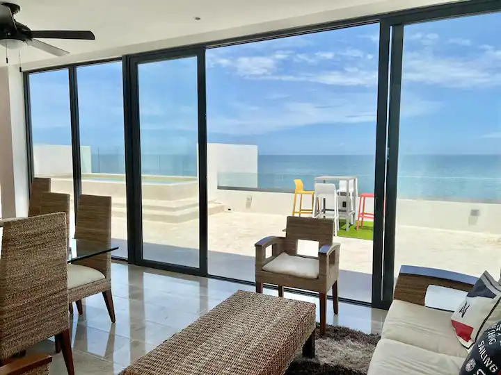 Living room with a view of the ocean through large glass doors.