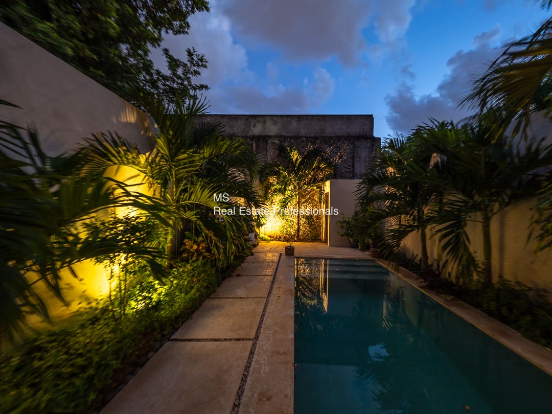 Nighttime poolside view, tropical garden.
