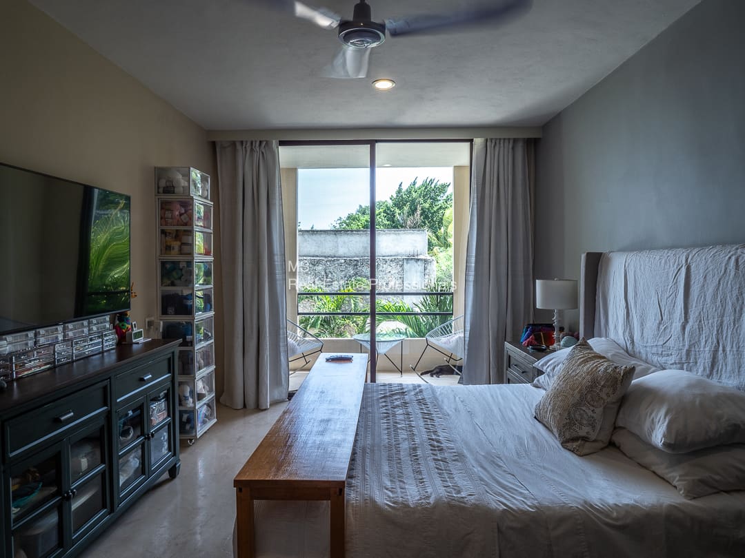 Bedroom with bed, balcony view, and storage.