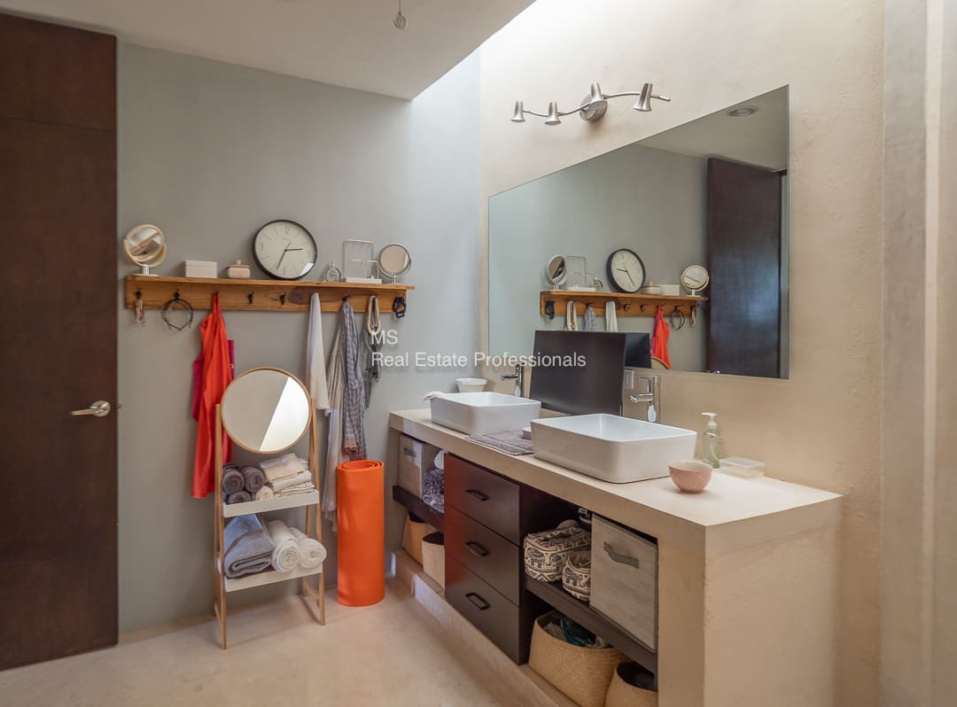 Modern bathroom with double sinks and storage.