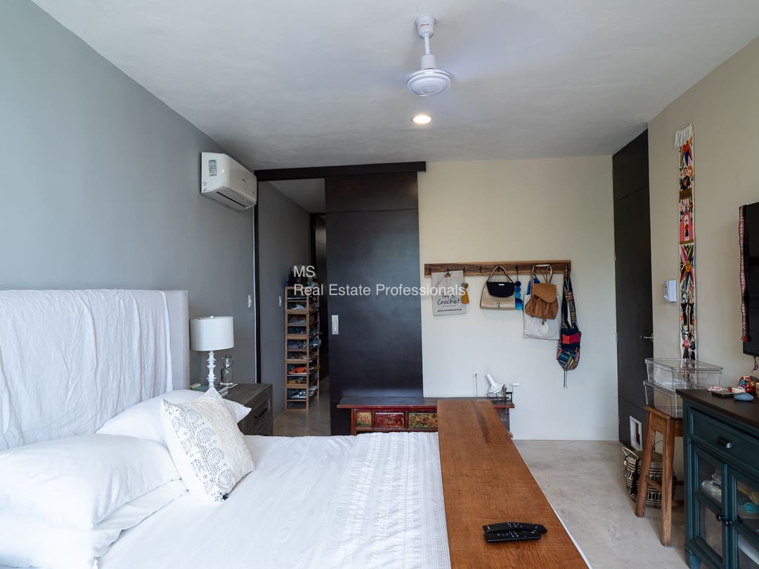 Modern bedroom with white bedding and wooden table.