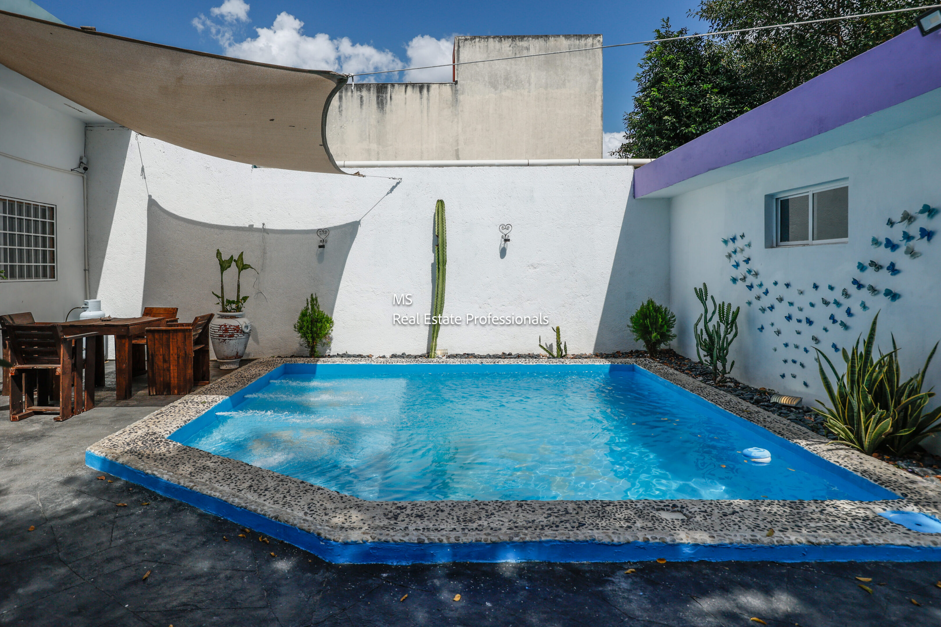 Here's an alt tag for the image: Small courtyard pool with patio furniture.