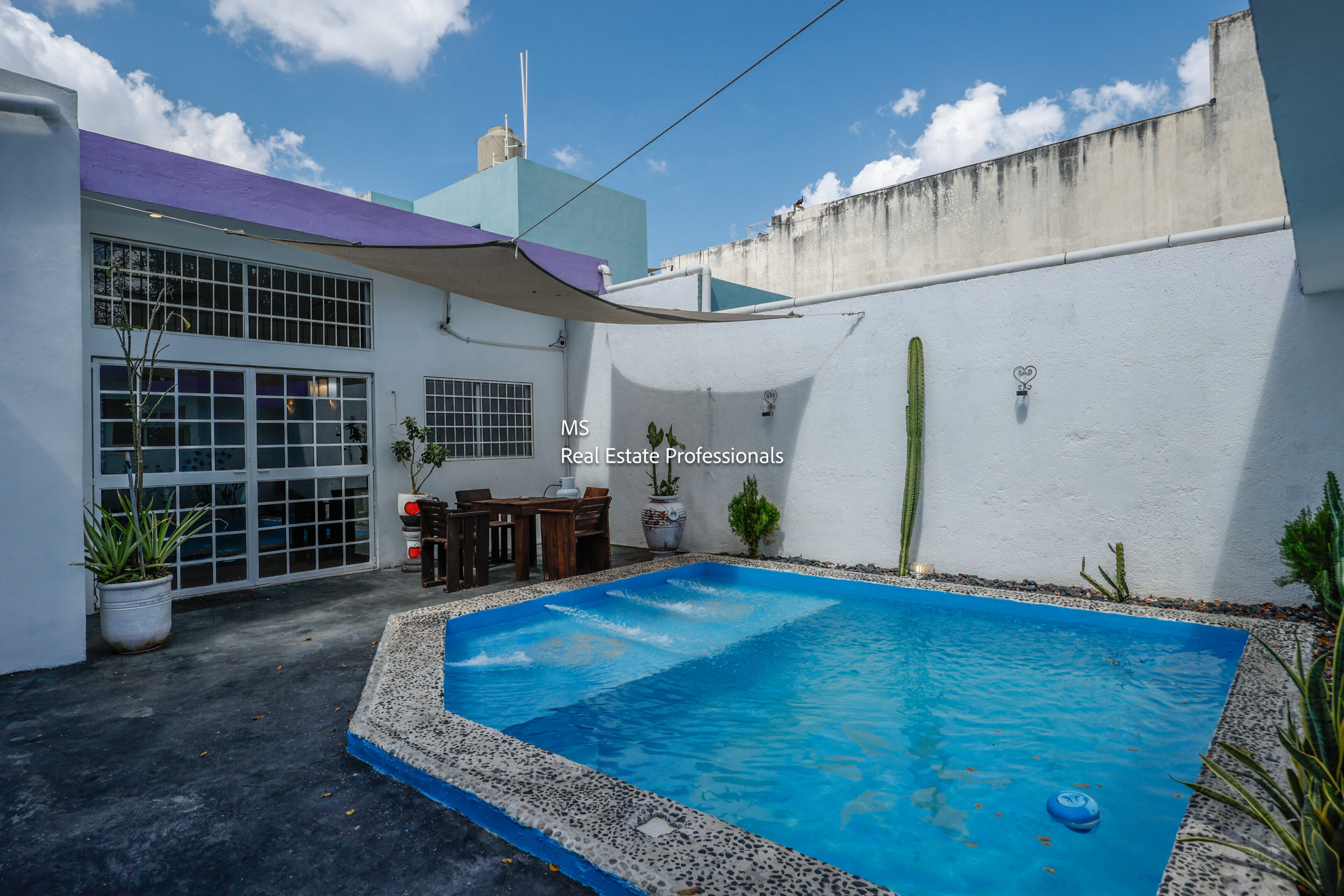 Here's an alt tag for the image: Small courtyard pool with patio furniture.