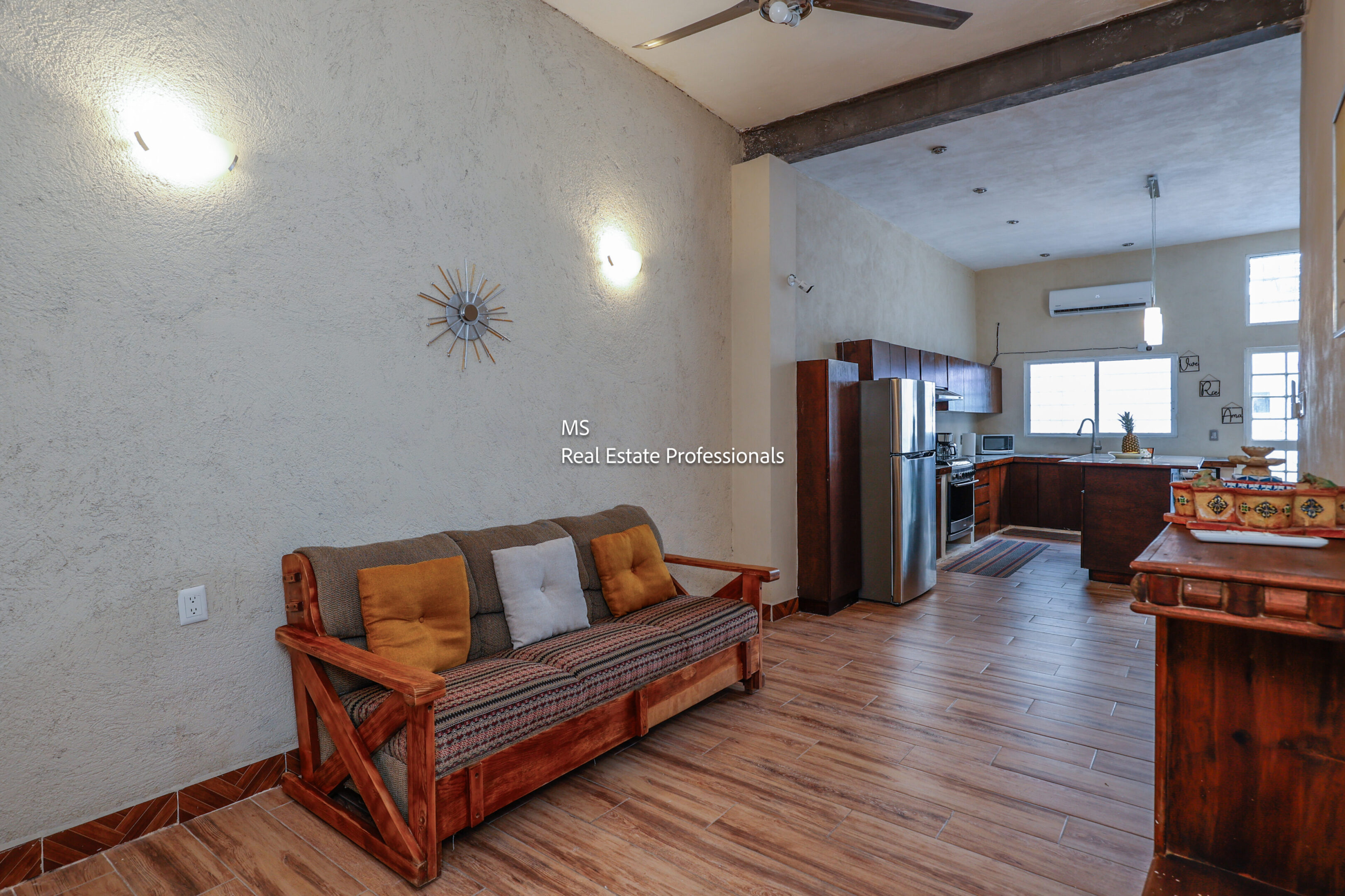 Wooden couch in living room with kitchen view.