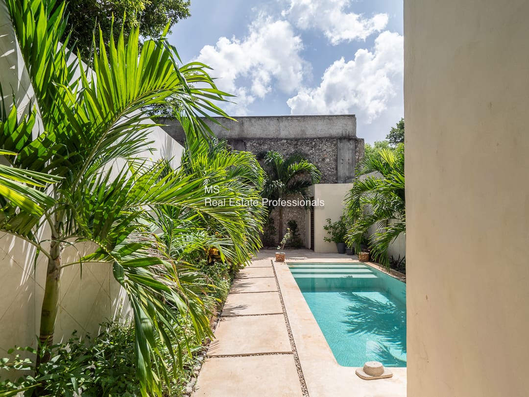 Tropical courtyard with pool and stone path.