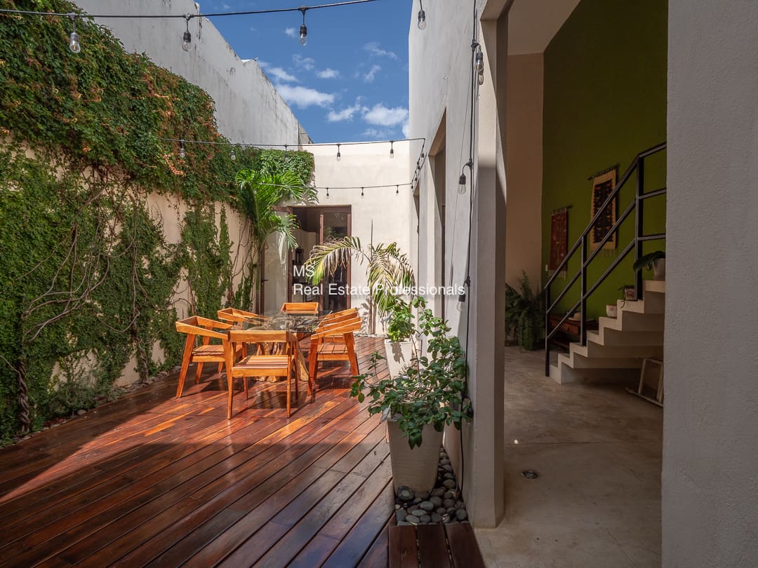 Sunlit patio with wooden table and chairs.