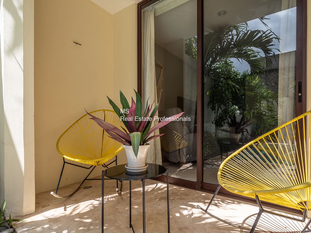 Patio with yellow rocking chairs and plant.