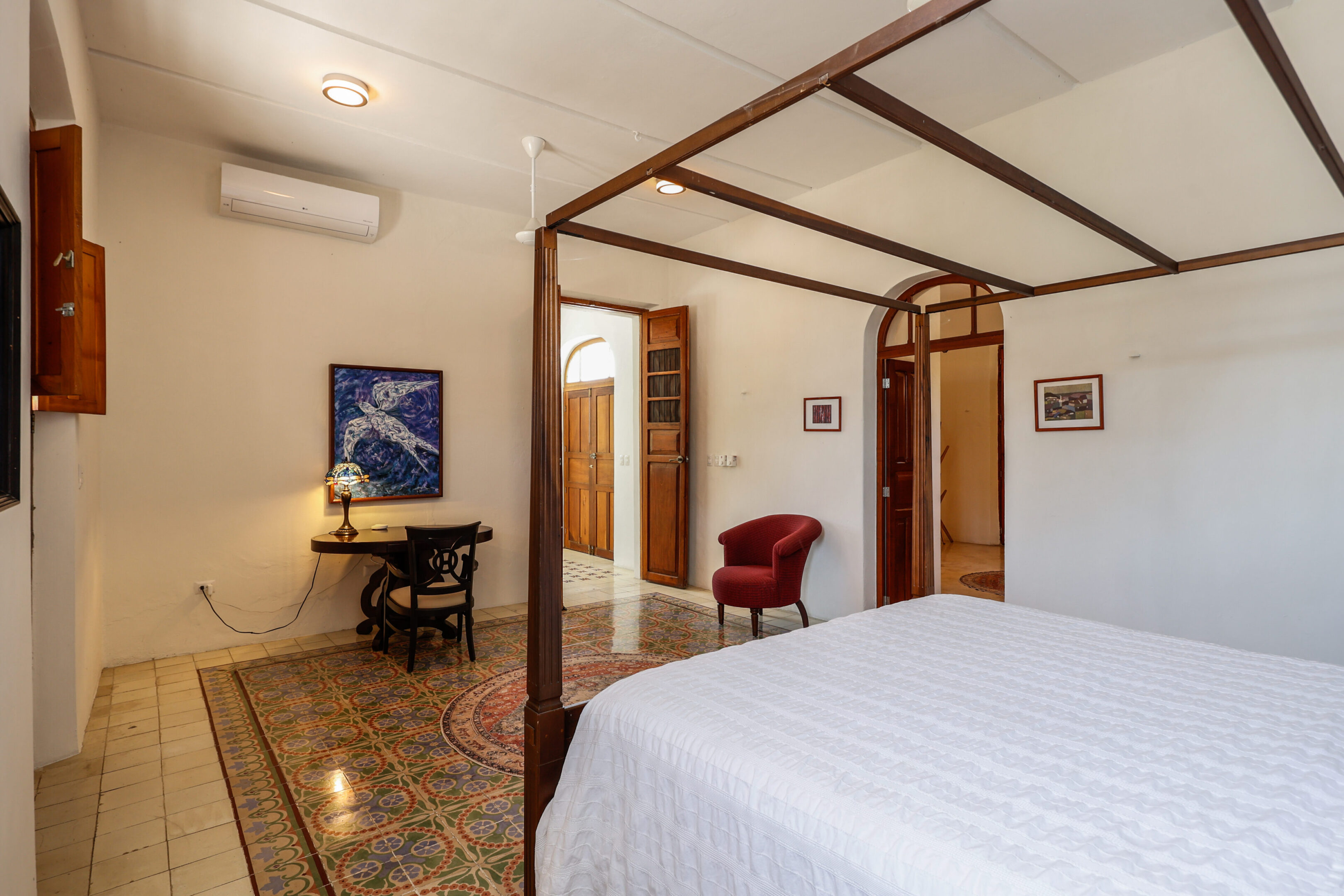 Bedroom with four-poster bed and tiled floor.