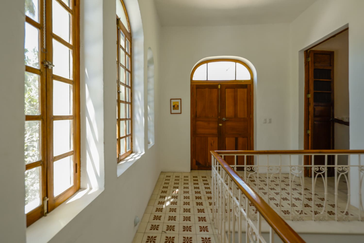 Sunlit hallway with wood door and windows.
