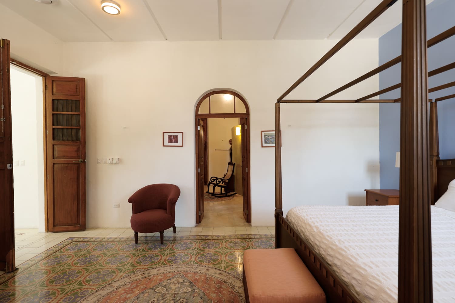 Bedroom with four-poster bed and tiled floor.