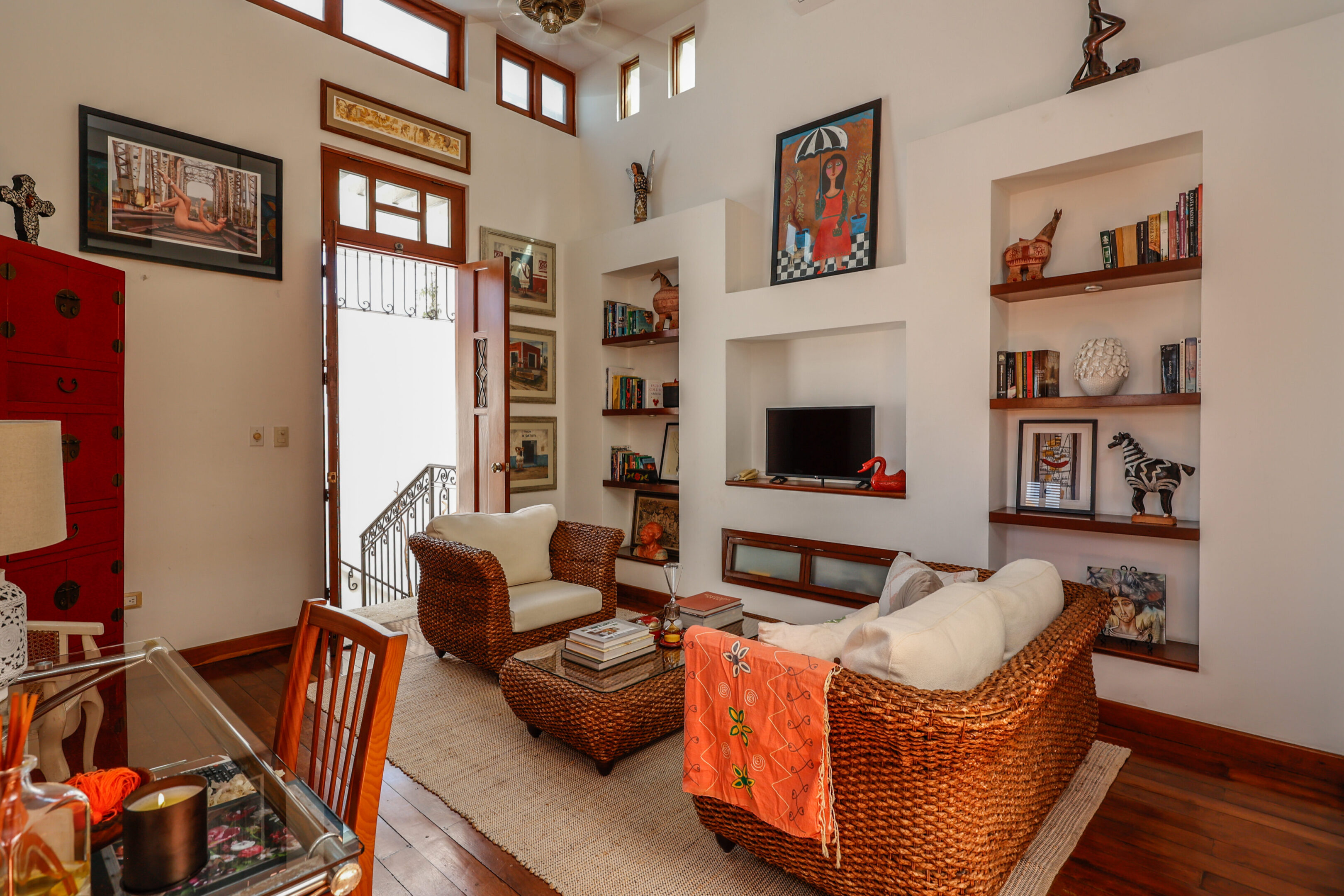 Art-filled living room with wicker furniture.