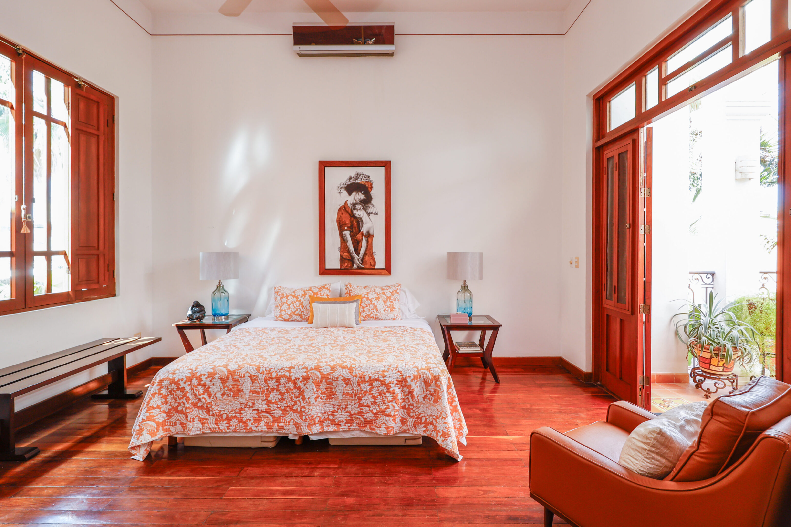 Bedroom with orange bedding and artwork.