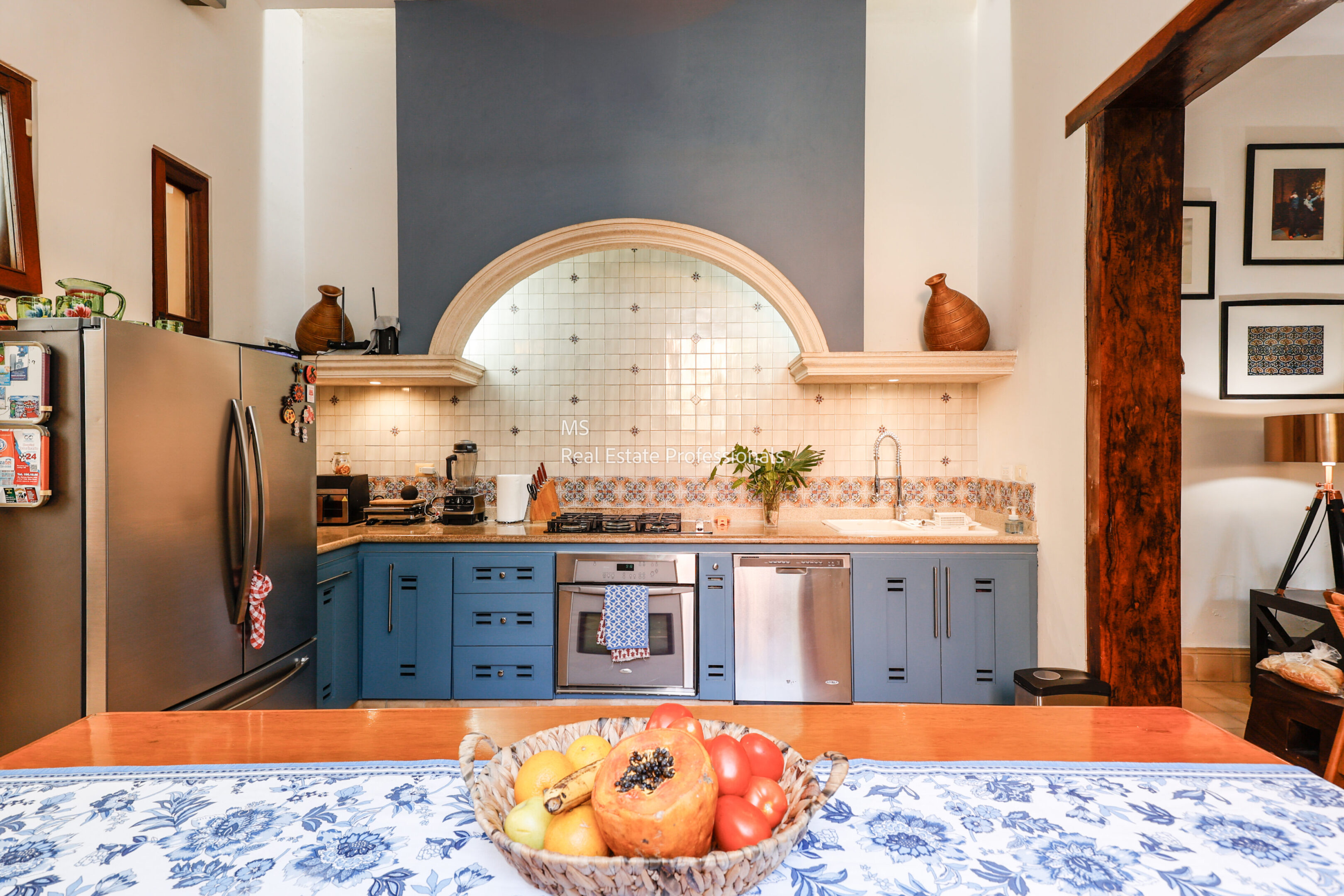 Blue kitchen with fruit bowl on table.