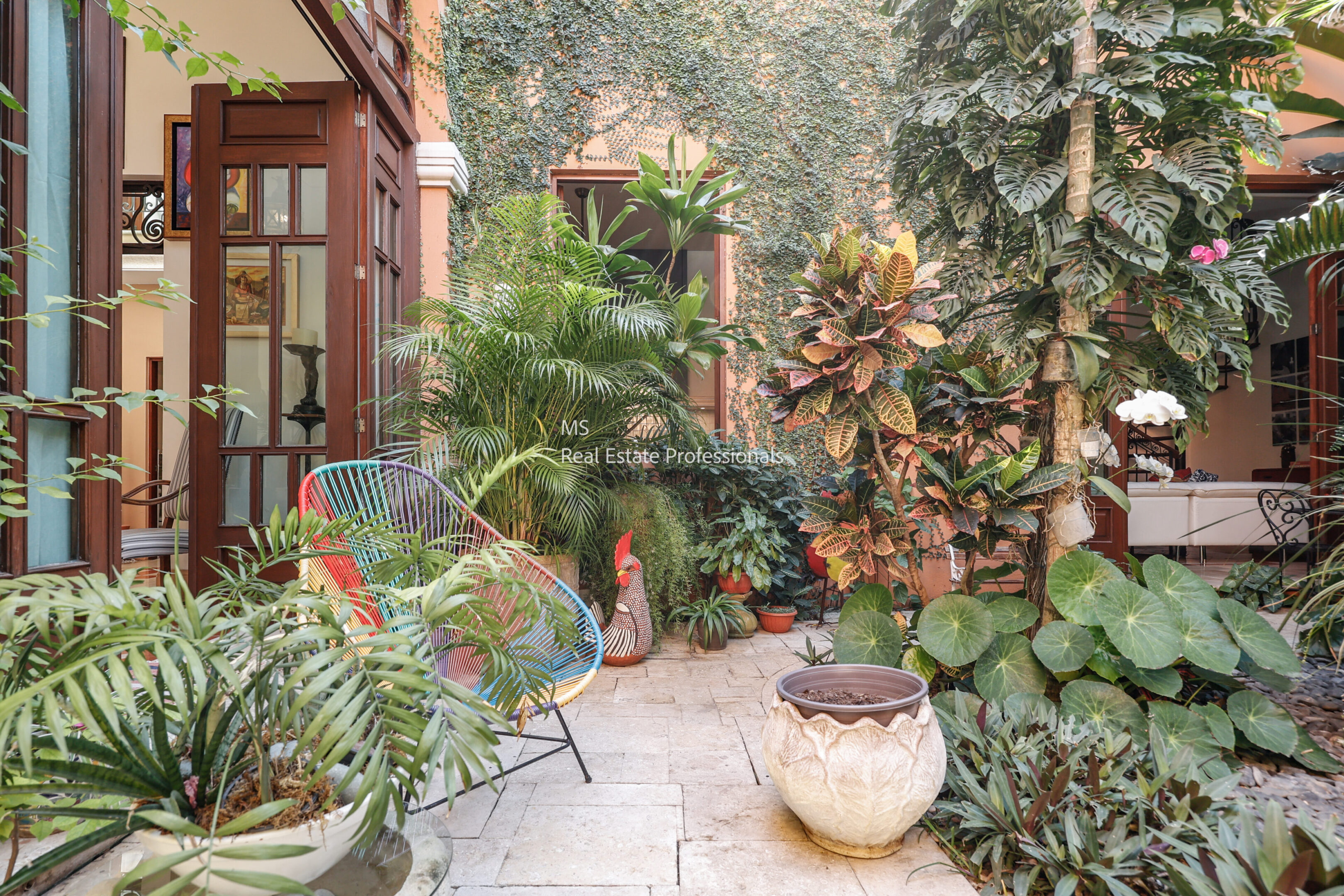 Lush tropical courtyard with colorful chair.