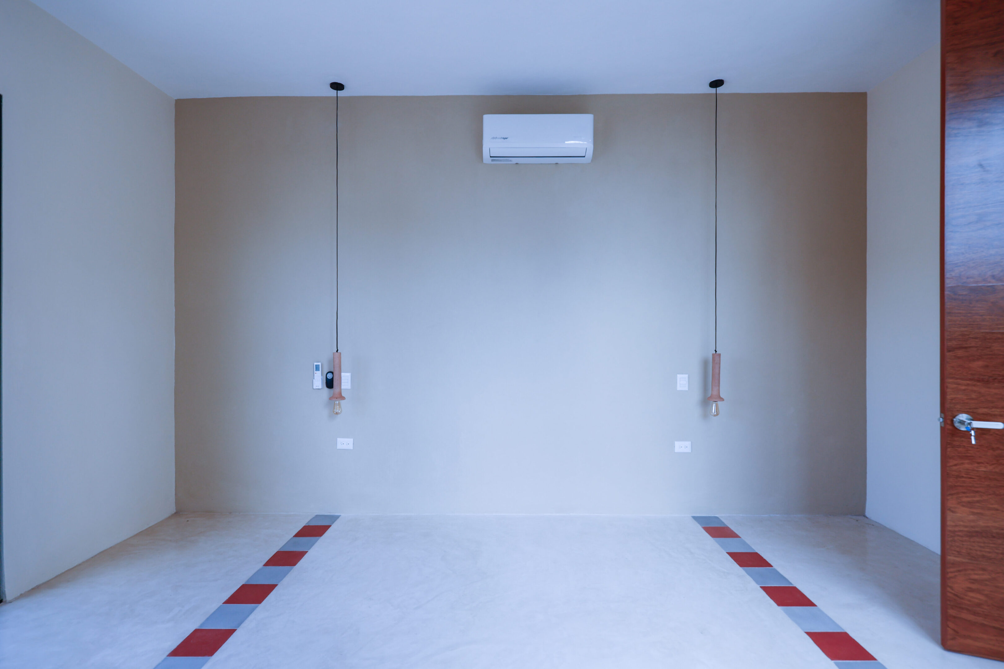 Minimalist room with two hanging pendant lights and air conditioner.