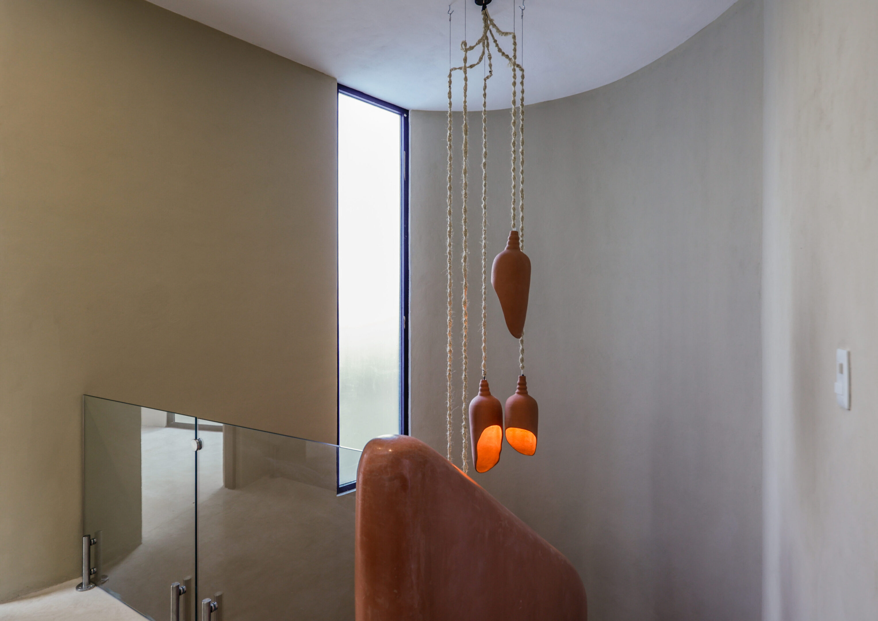 A modern light fixture with orange bulbs hangs in a minimalistic room.