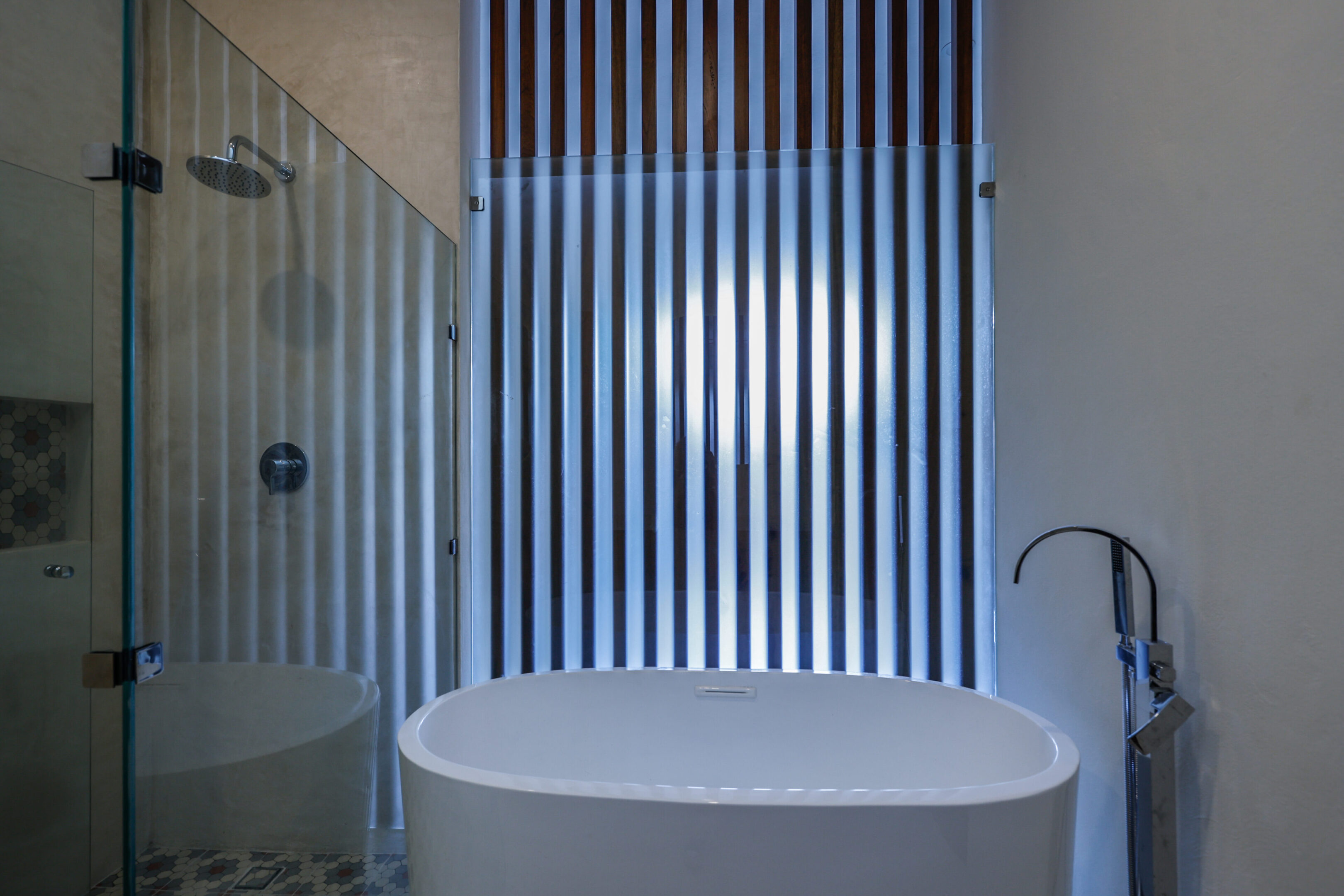 Modern bathroom with a white oval bathtub and vertical striped wall.