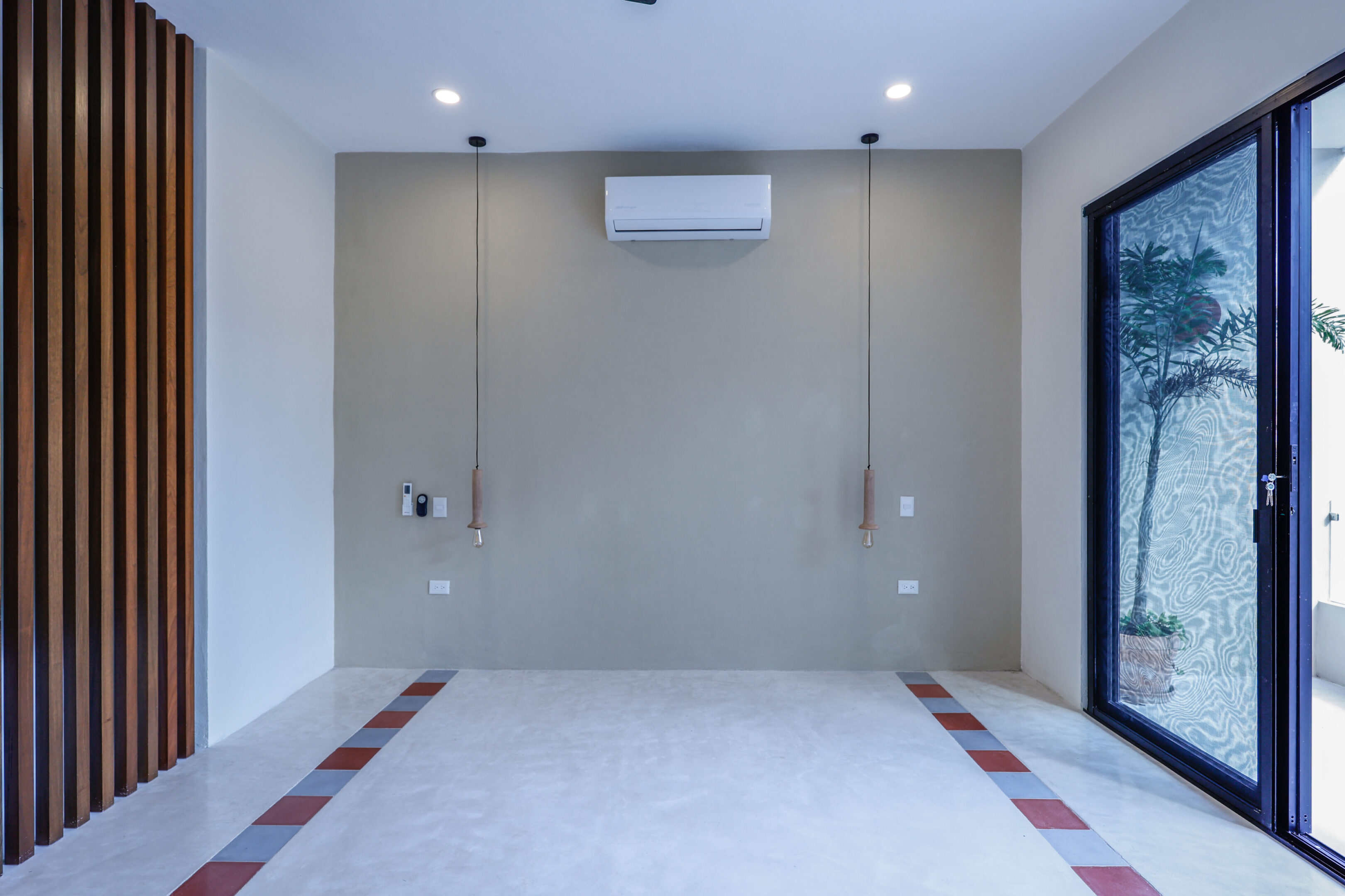 A modern, minimalistic room with a concrete accent wall and hanging light bulbs.