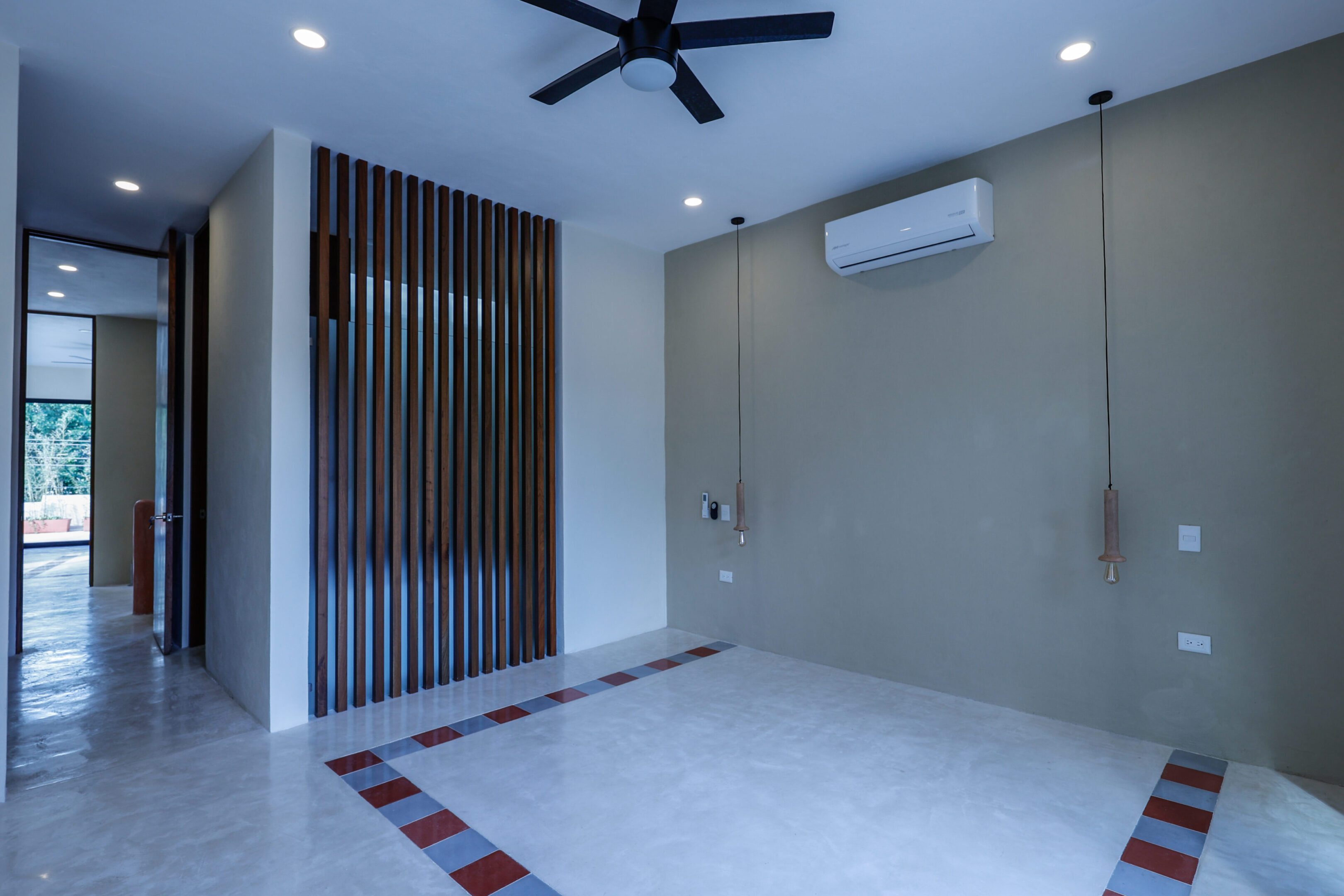 A clean, empty room with a ceiling fan and air conditioner.