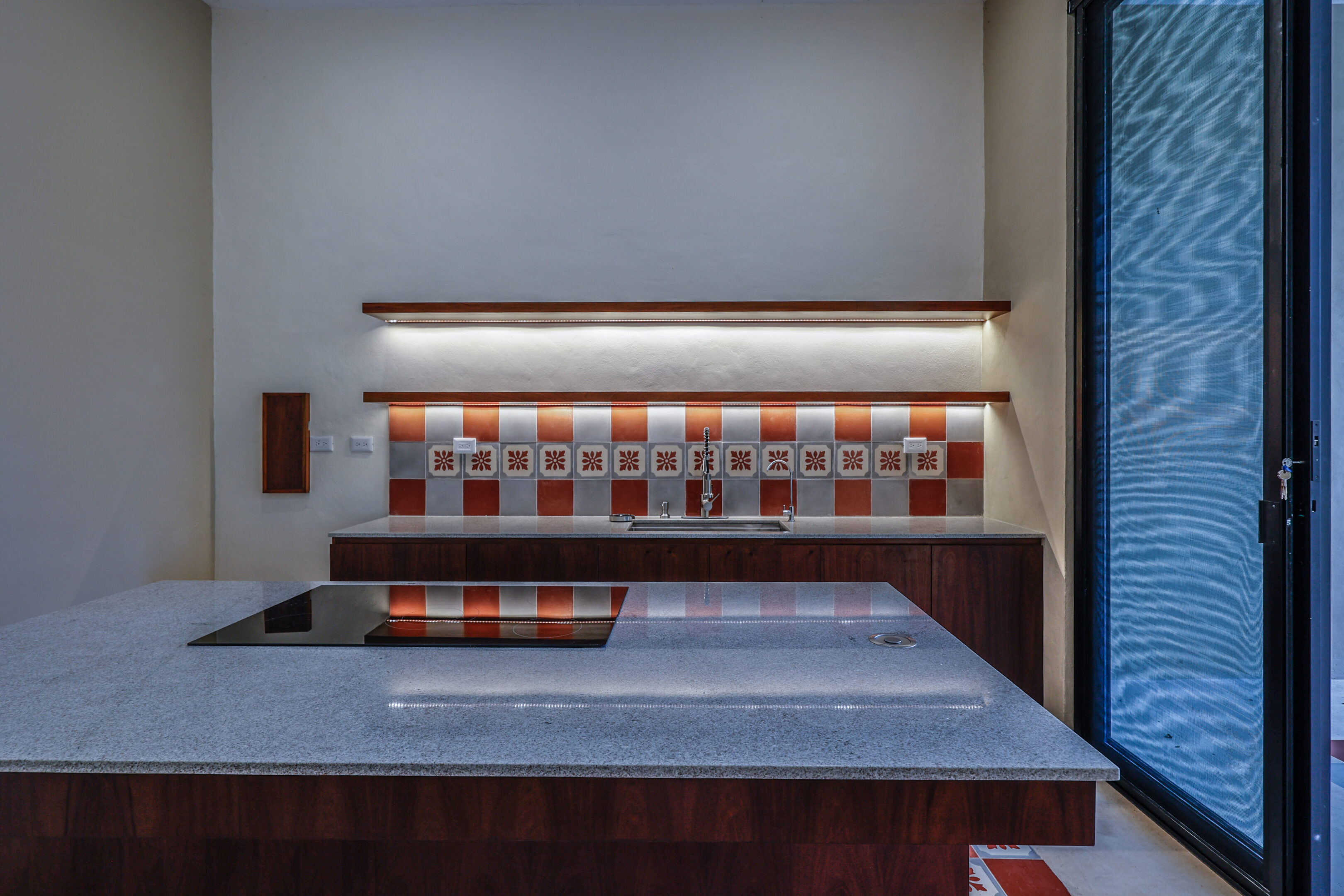 A modern kitchen counter with a tiled backsplash and under-cabinet lighting.
