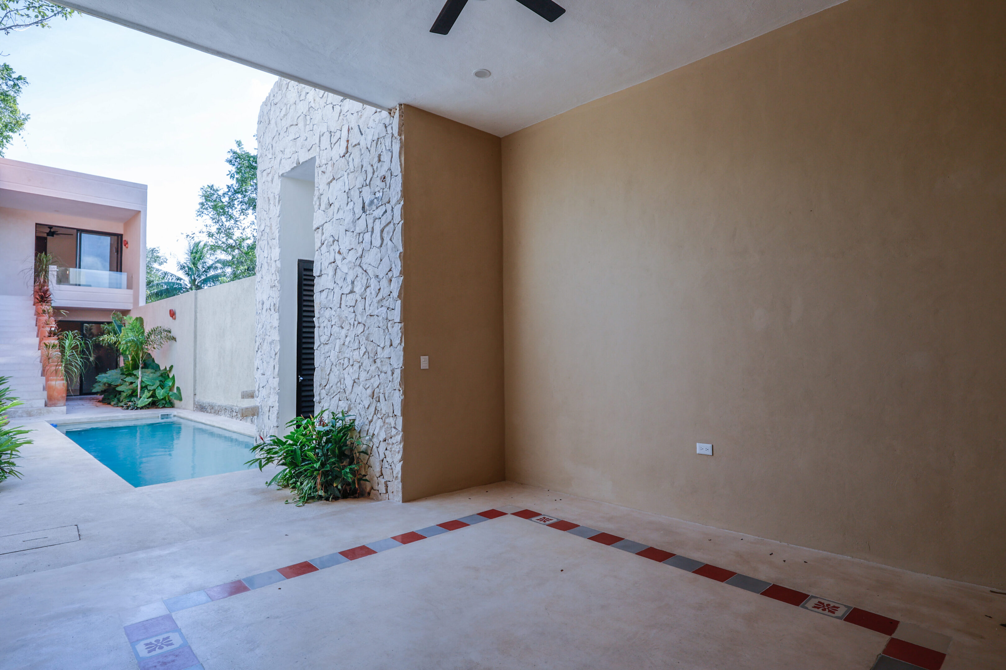 A shaded patio with a ceiling fan overlooking a small pool.