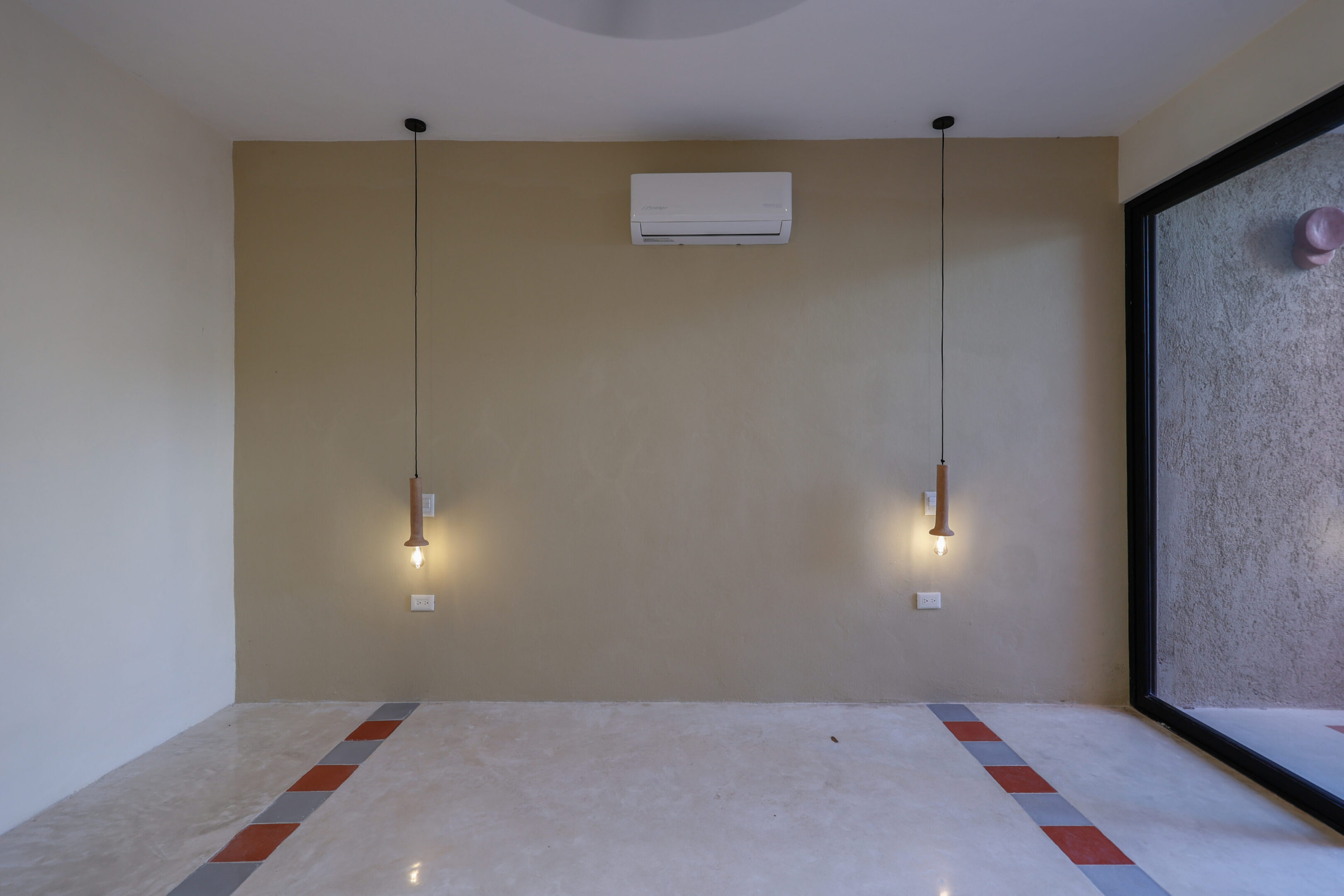 Two minimalist pendant lights hanging on a beige wall above a marble floor.