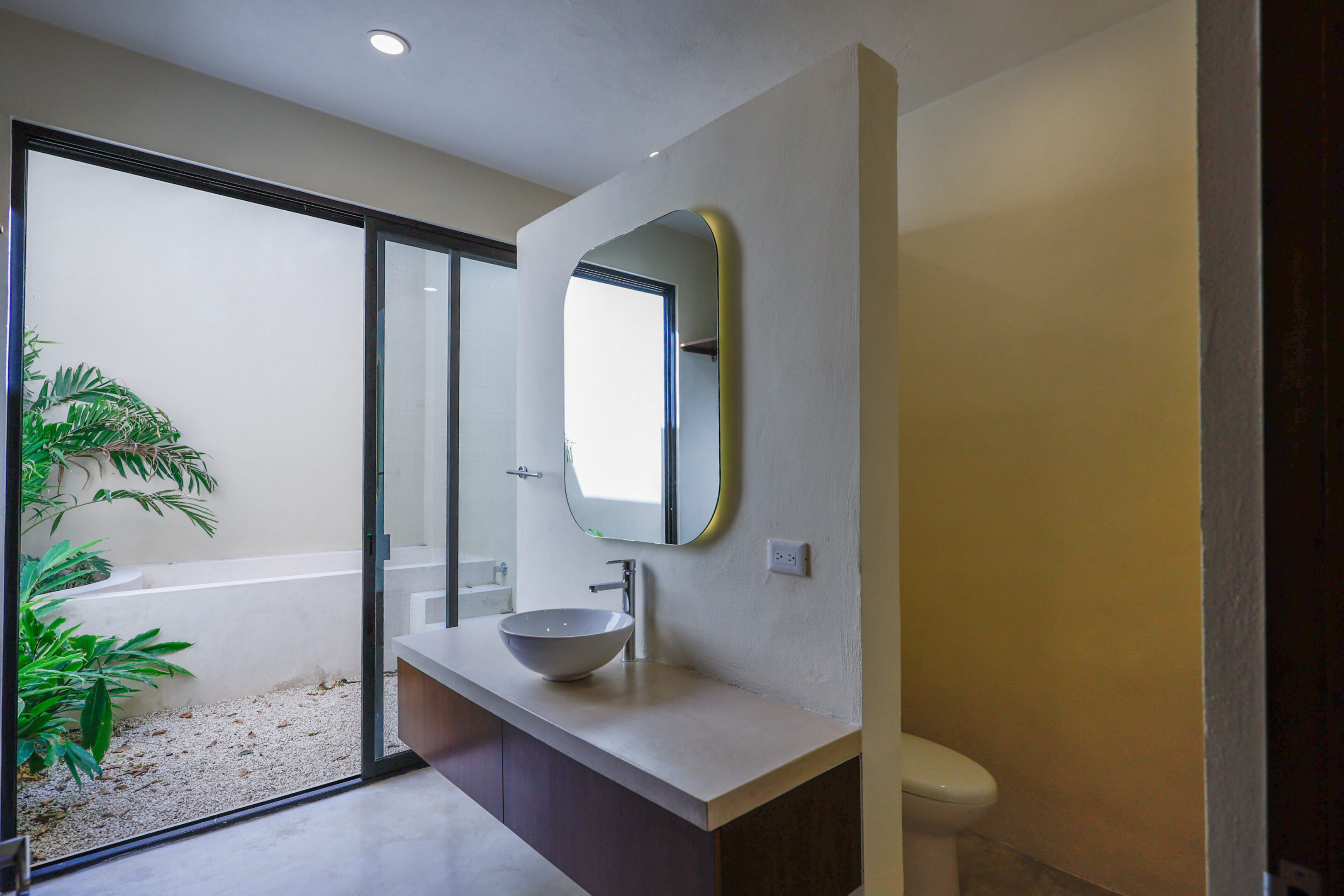 Modern bathroom with a floating sink and oval mirror.