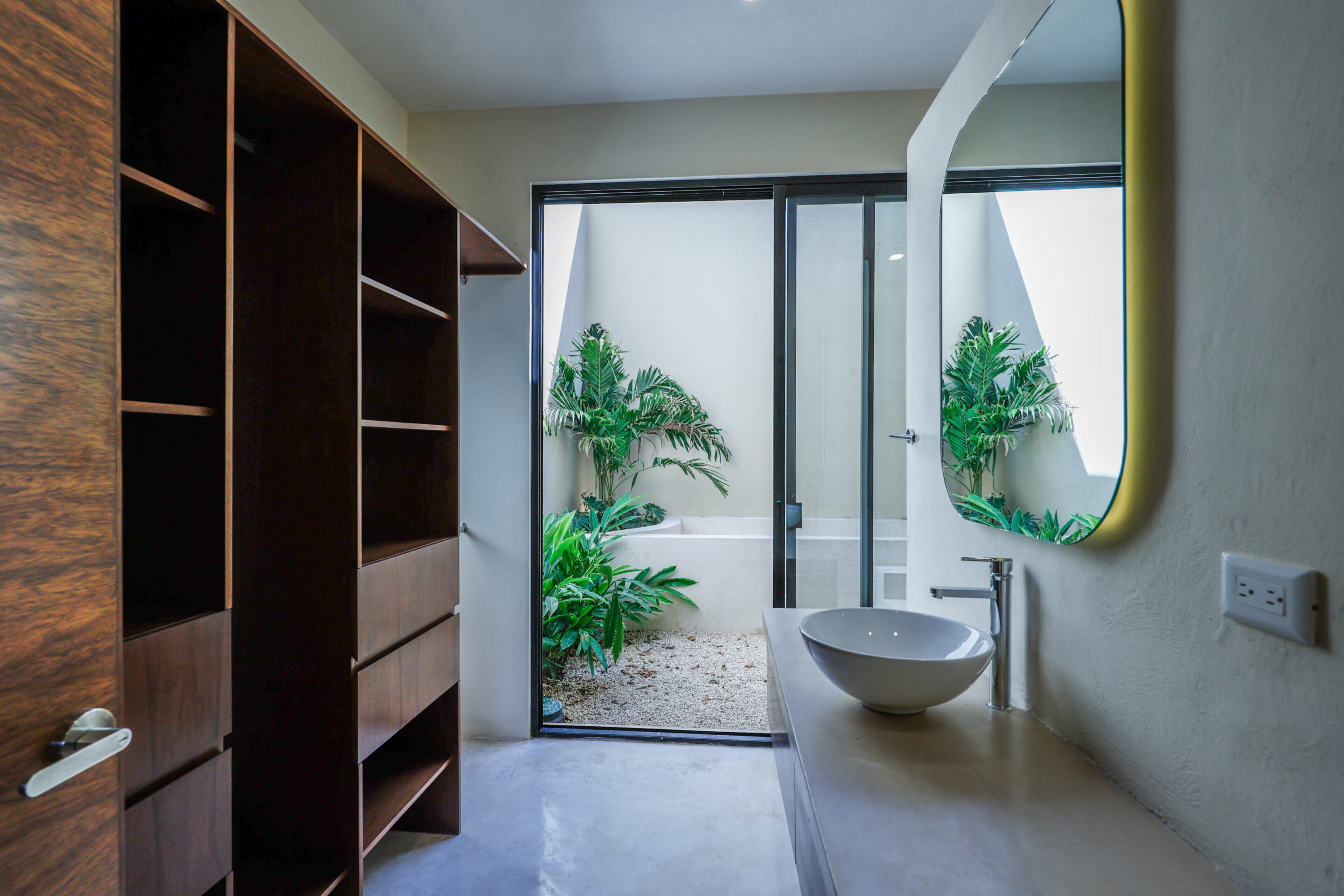 Minimalist bathroom with a stone sink and outdoor plants.