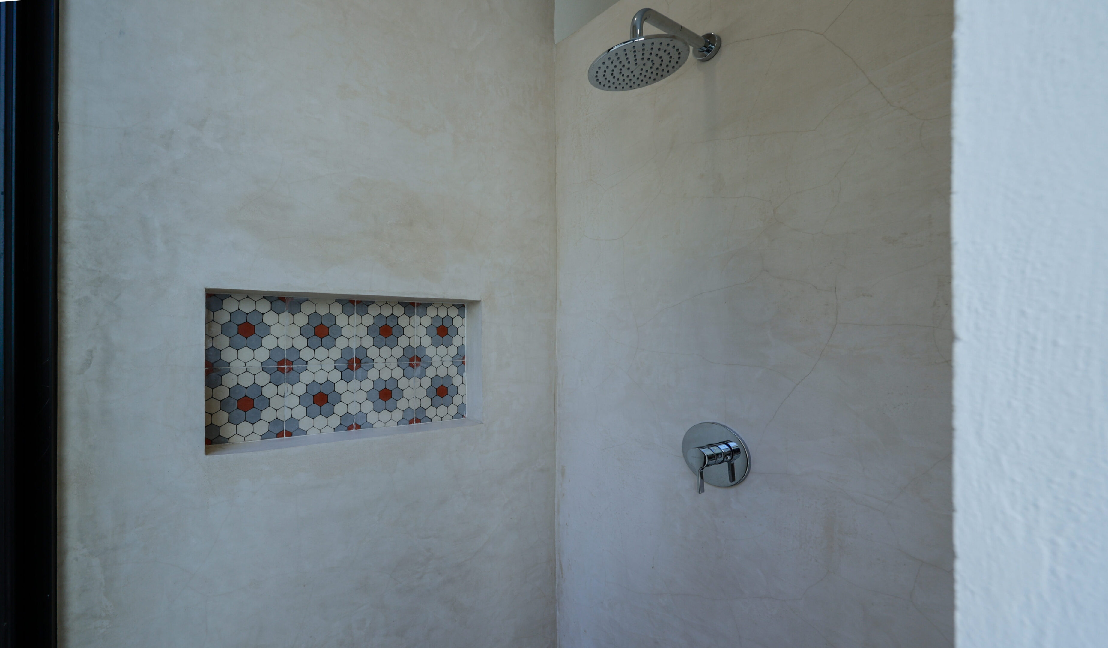 Minimalist shower with built-in niche and overhead showerhead.