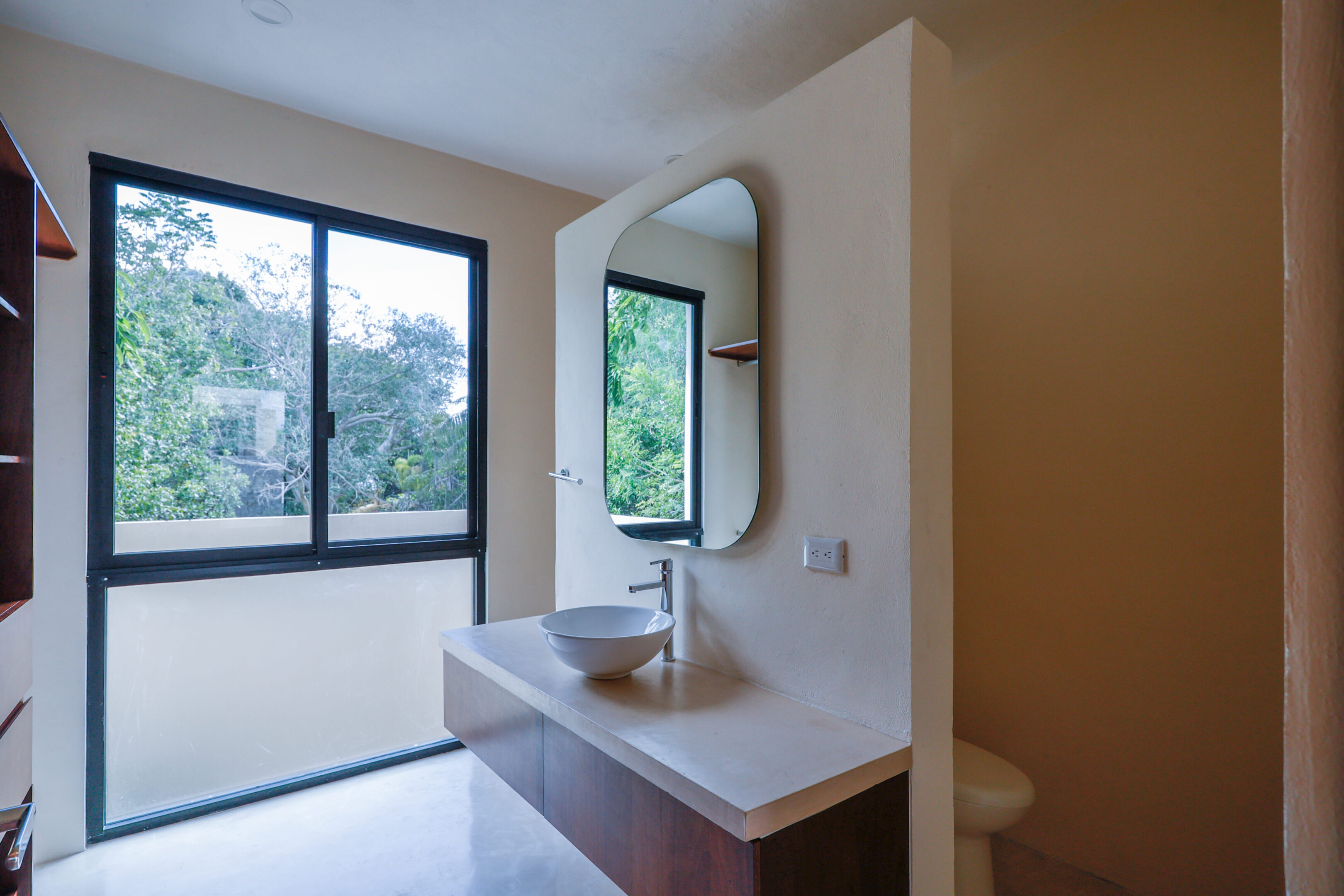 Modern bathroom sink with large mirror and windows.