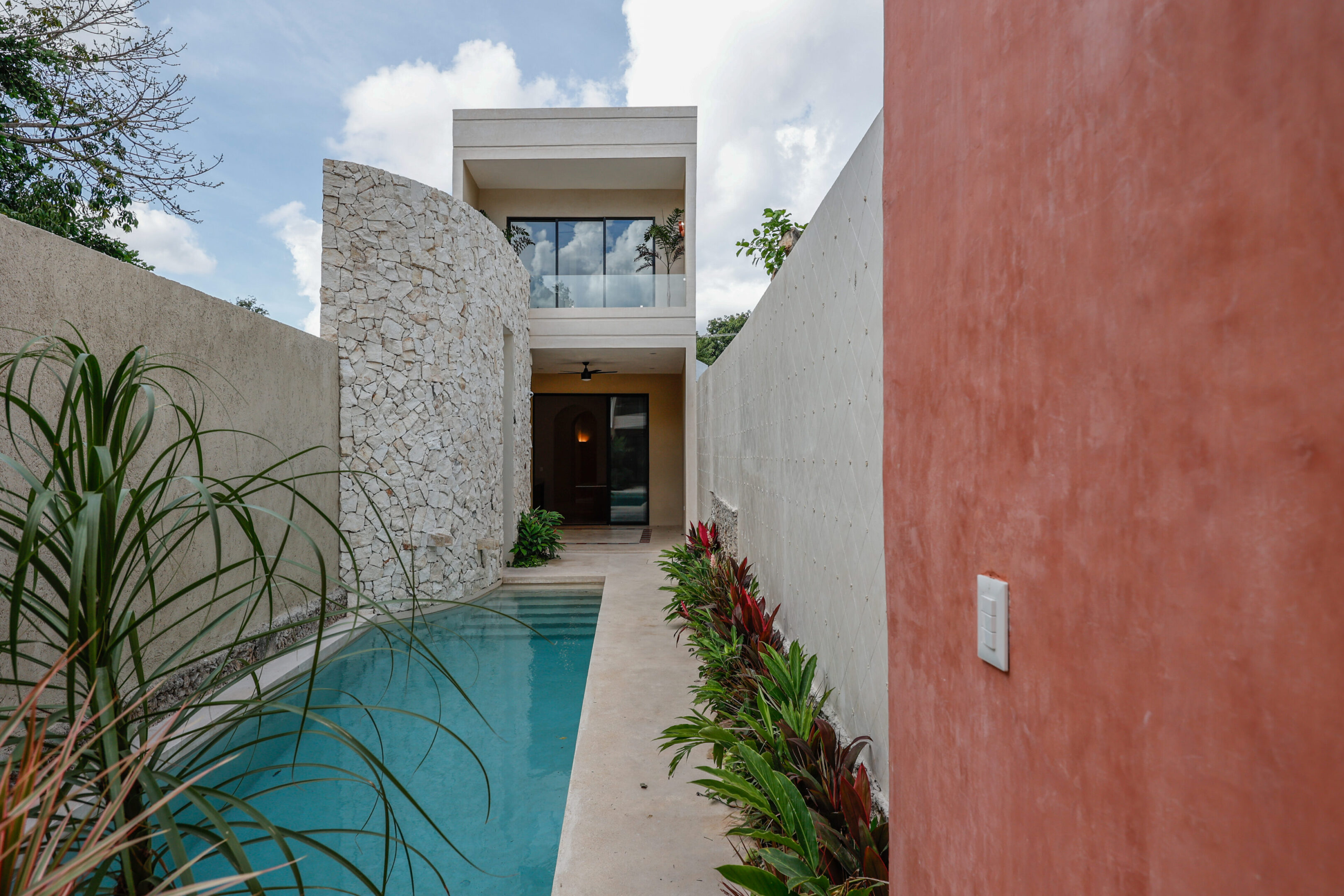 Modern house entrance with a pool and stone wall.