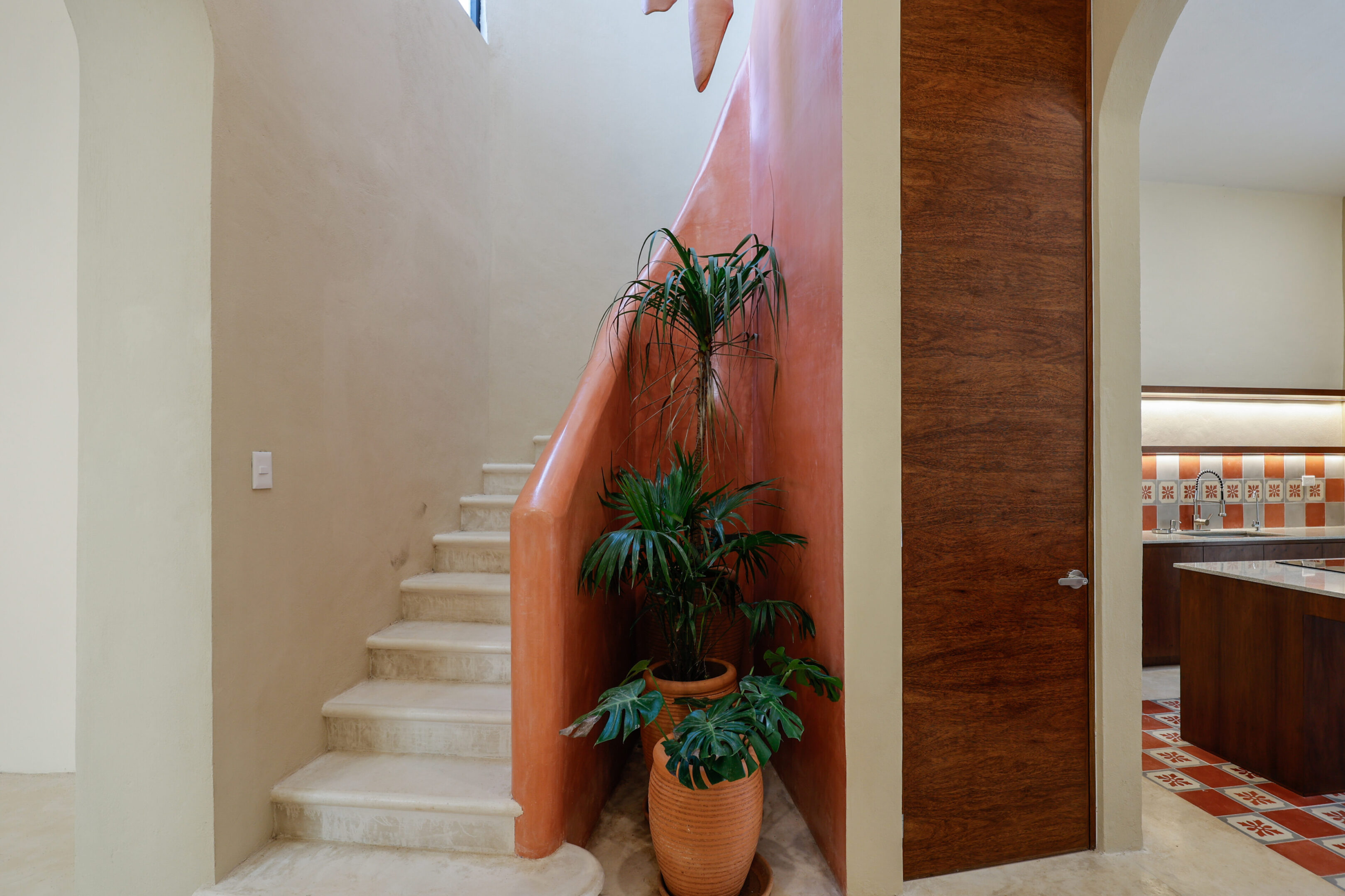 Indoor staircase corner with potted plants and textured wall.