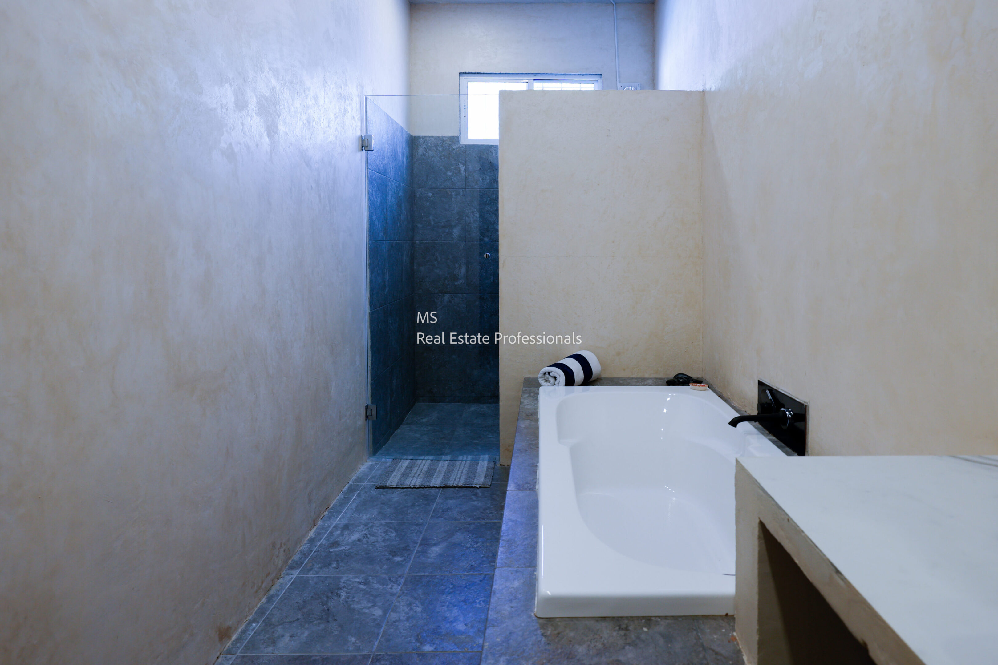 Modern bathroom with a bathtub and walk-in shower separated by a partial wall.