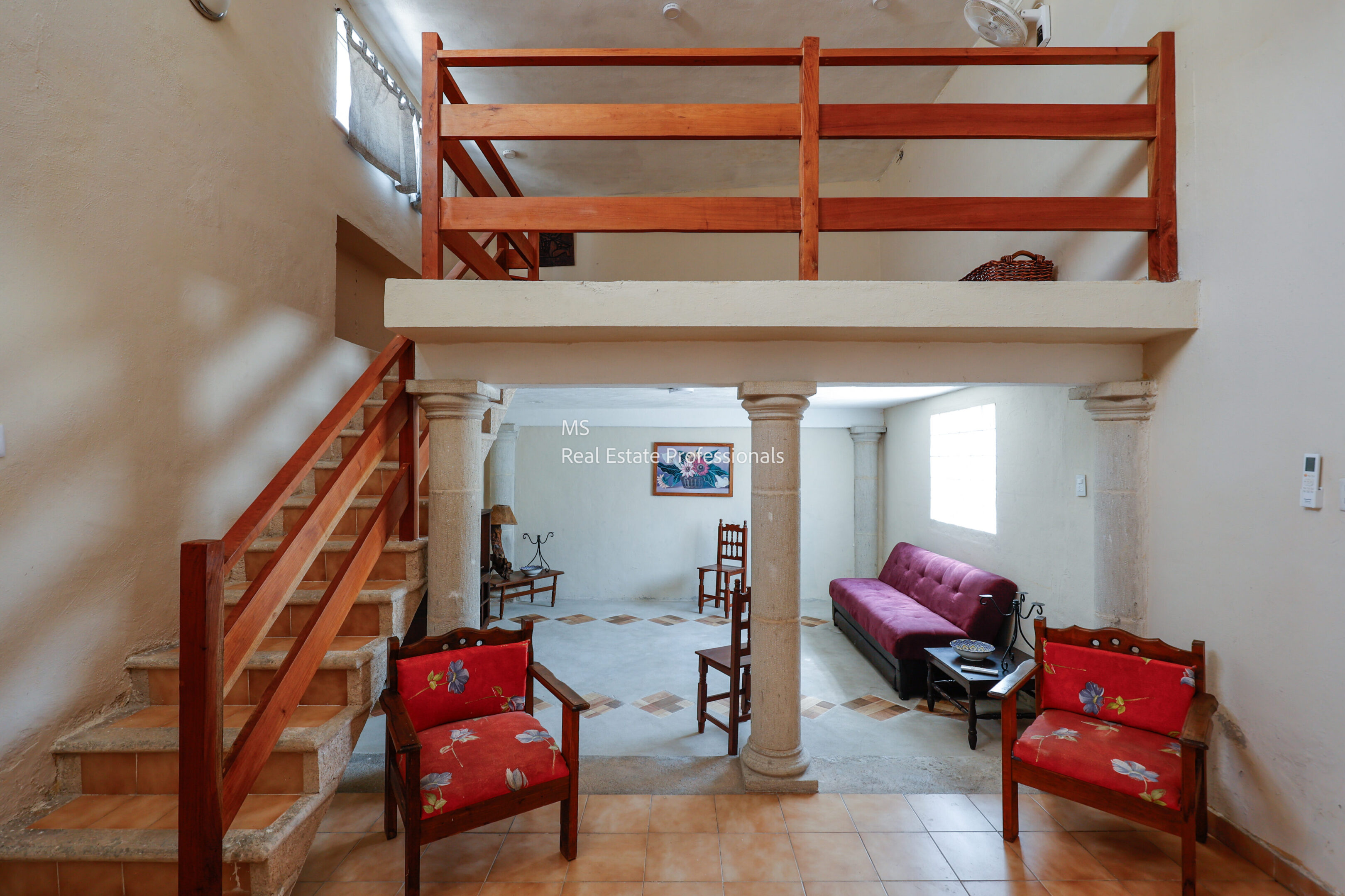 Cozy living room with red armchairs and a loft area above.
