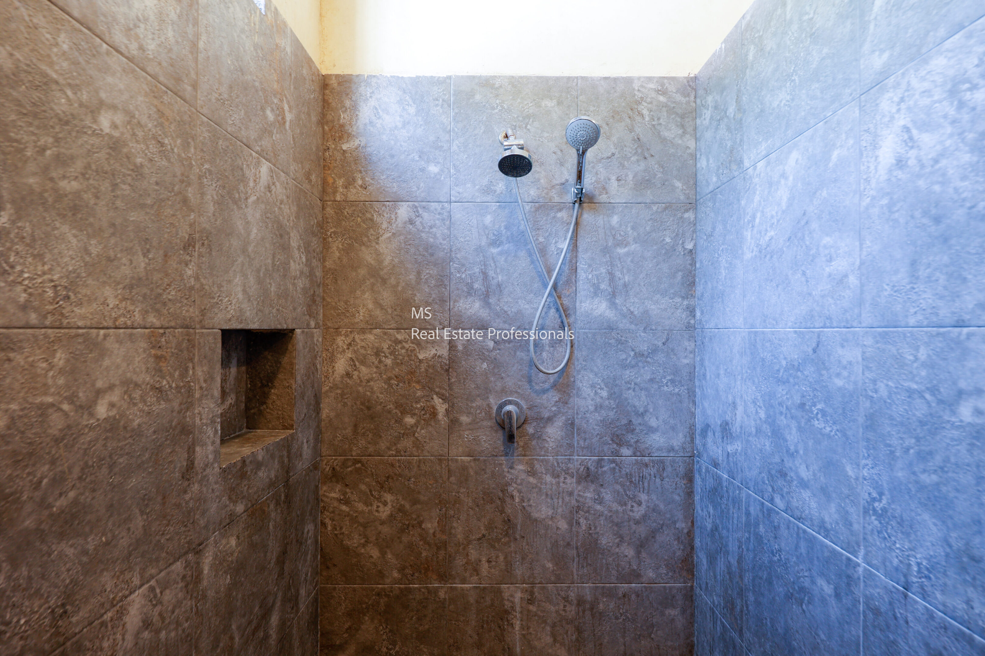 A modern marble shower stall with built-in niche and rain showerhead.