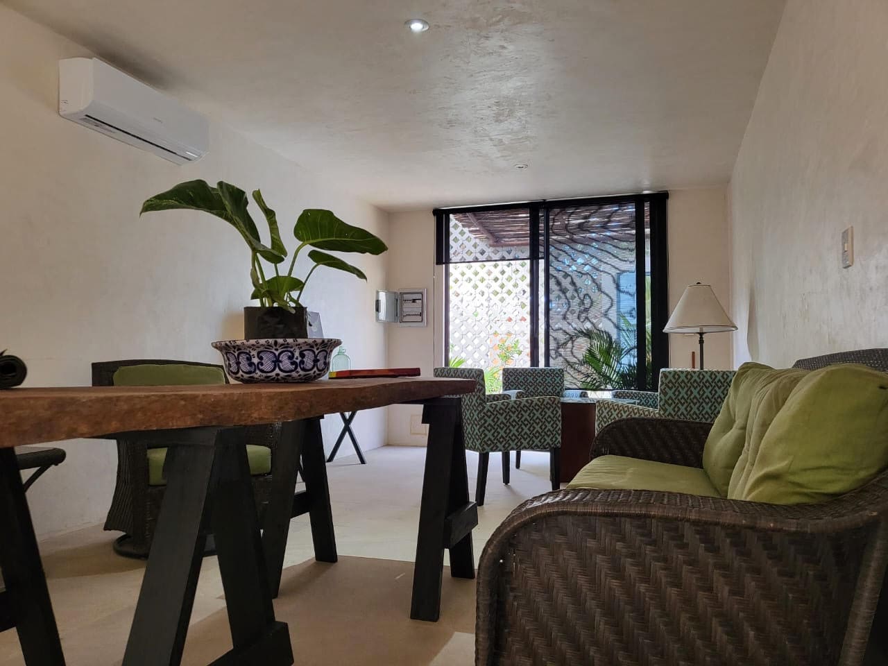 Cozy living area with plants and seating by large windows.
