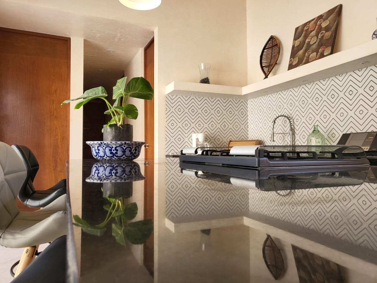 Modern kitchen with reflective countertops and blue patterned planters.