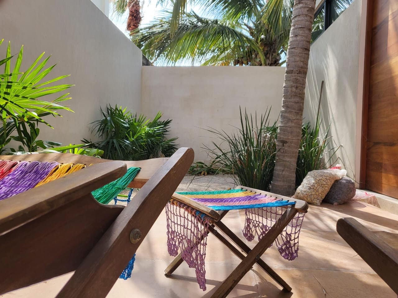 A cozy patio with wooden furniture and tropical plants.