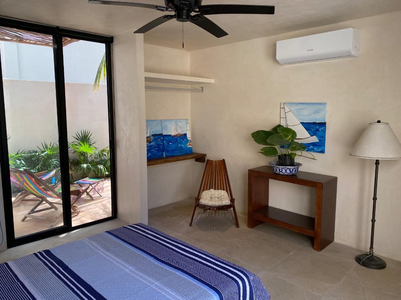 A cozy bedroom with a chair, desk, and ocean-themed artwork.