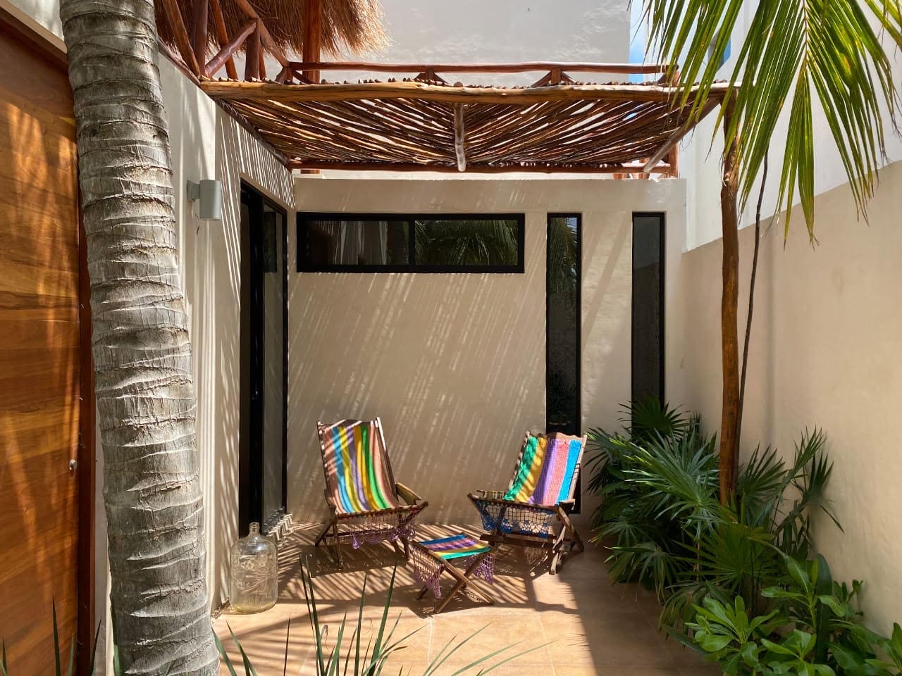 Cozy outdoor seating area with striped chairs under a wooden pergola.