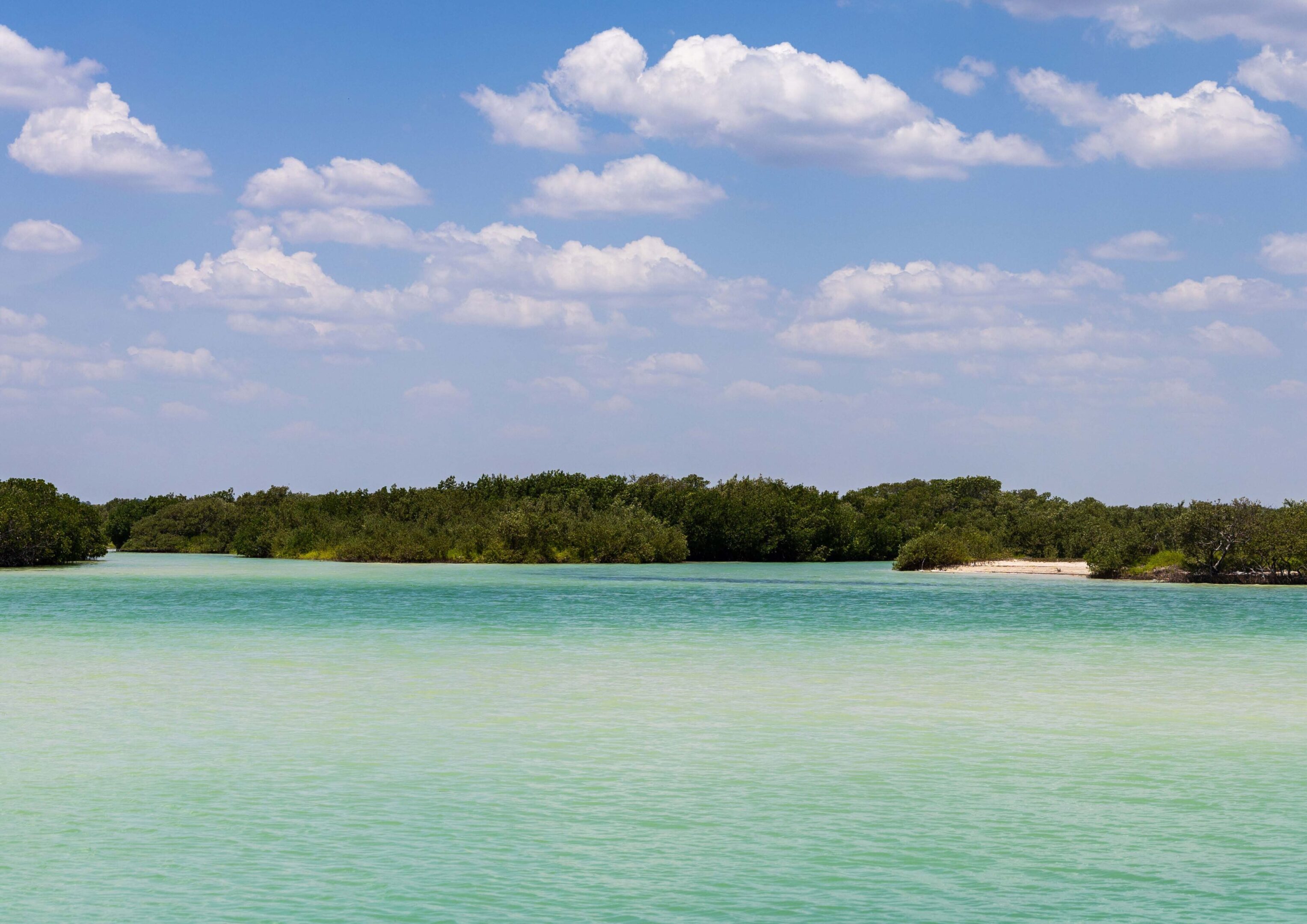 A serene lake with turquoise water under a partly cloudy sky.