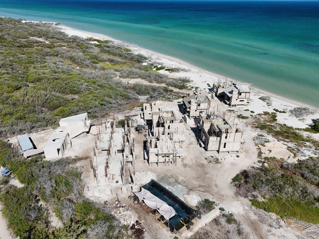 Aerial view of ancient ruins near a turquoise coastline.