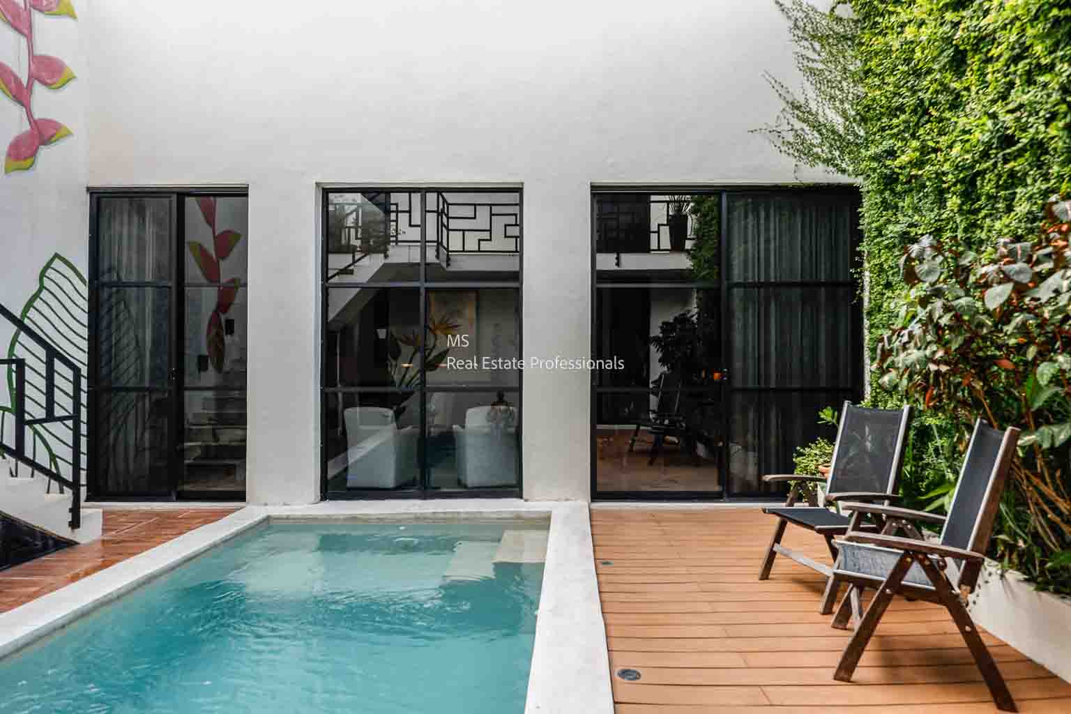 Modern poolside area with white walls and wooden deck chairs.