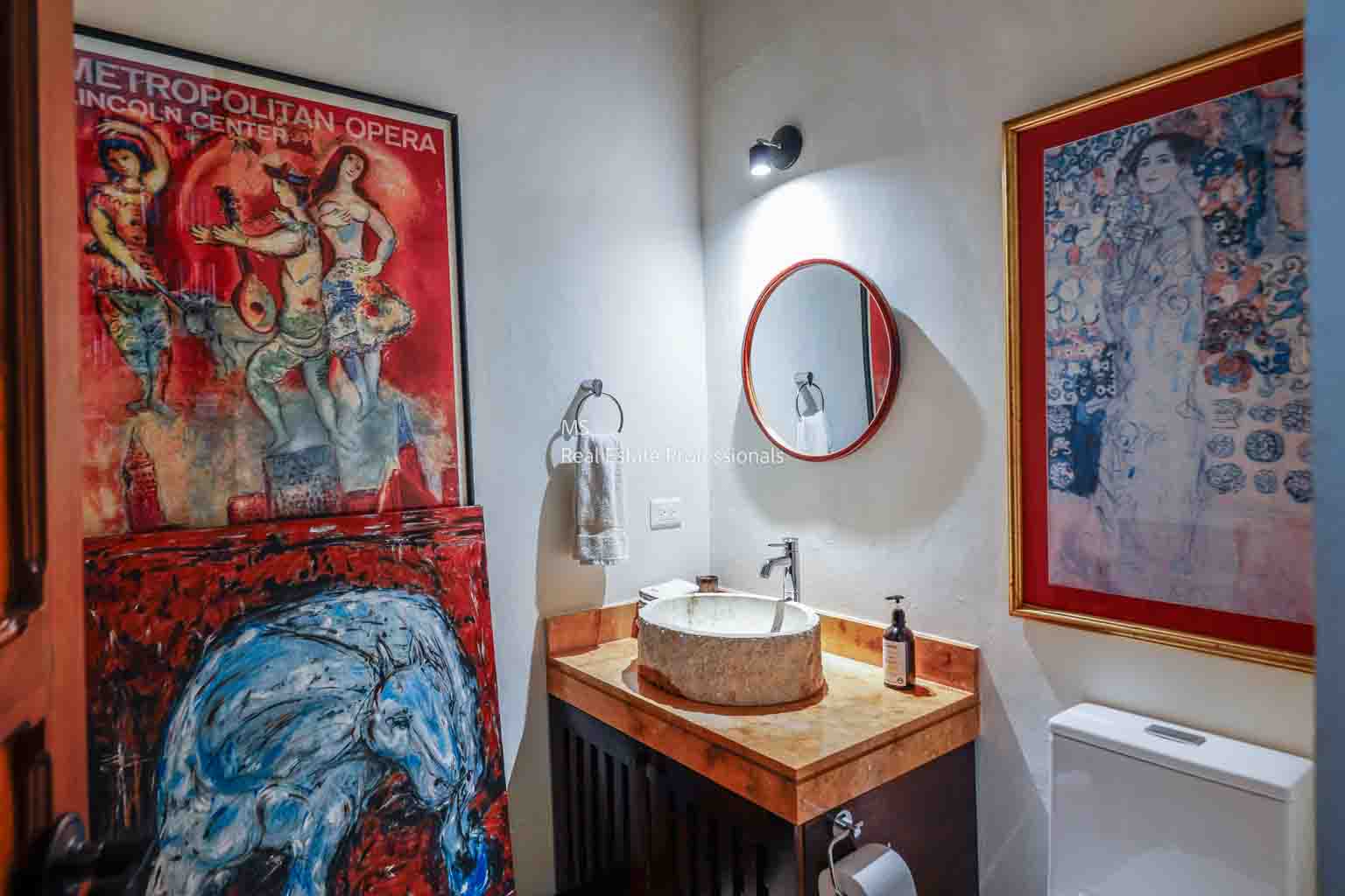 A modern bathroom with artistic decor and wooden vanity.