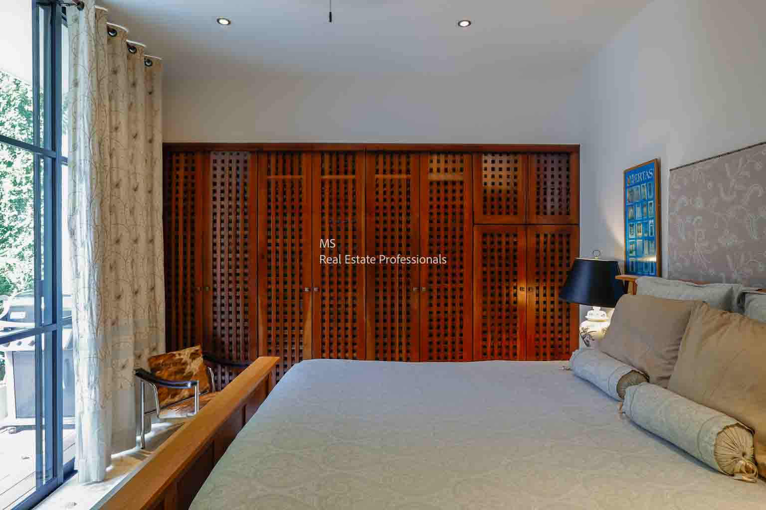 Modern bedroom with wooden wardrobe and cozy bed.