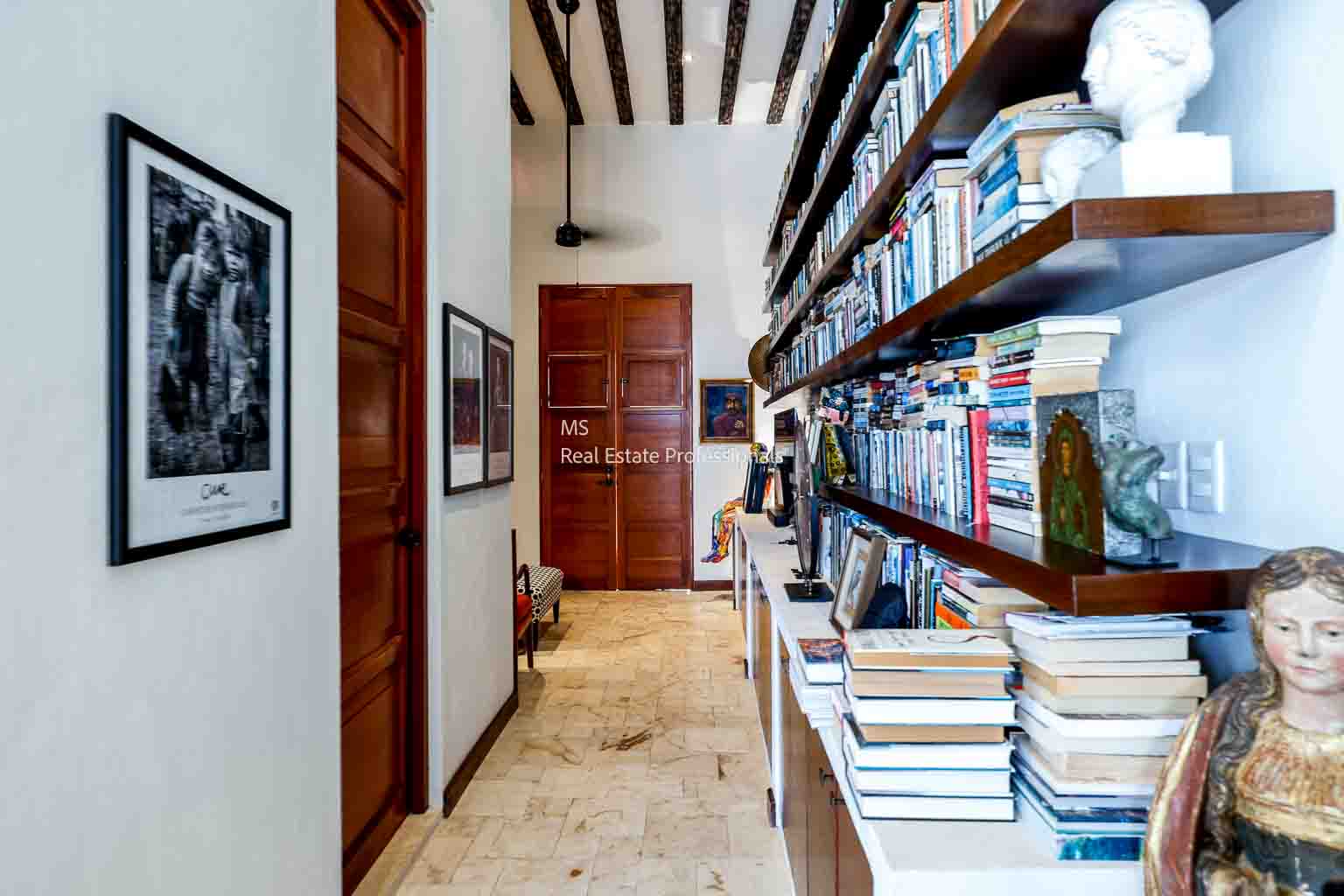 Cozy hallway with wooden beams and shelves filled with books.