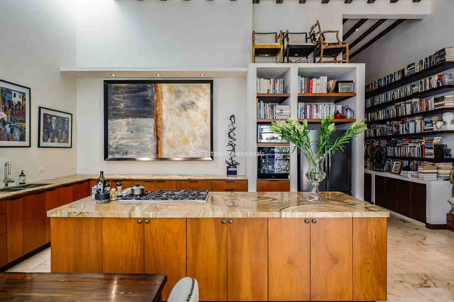 A modern wooden kitchen counter with a glass vase and abstract art on the wall.
